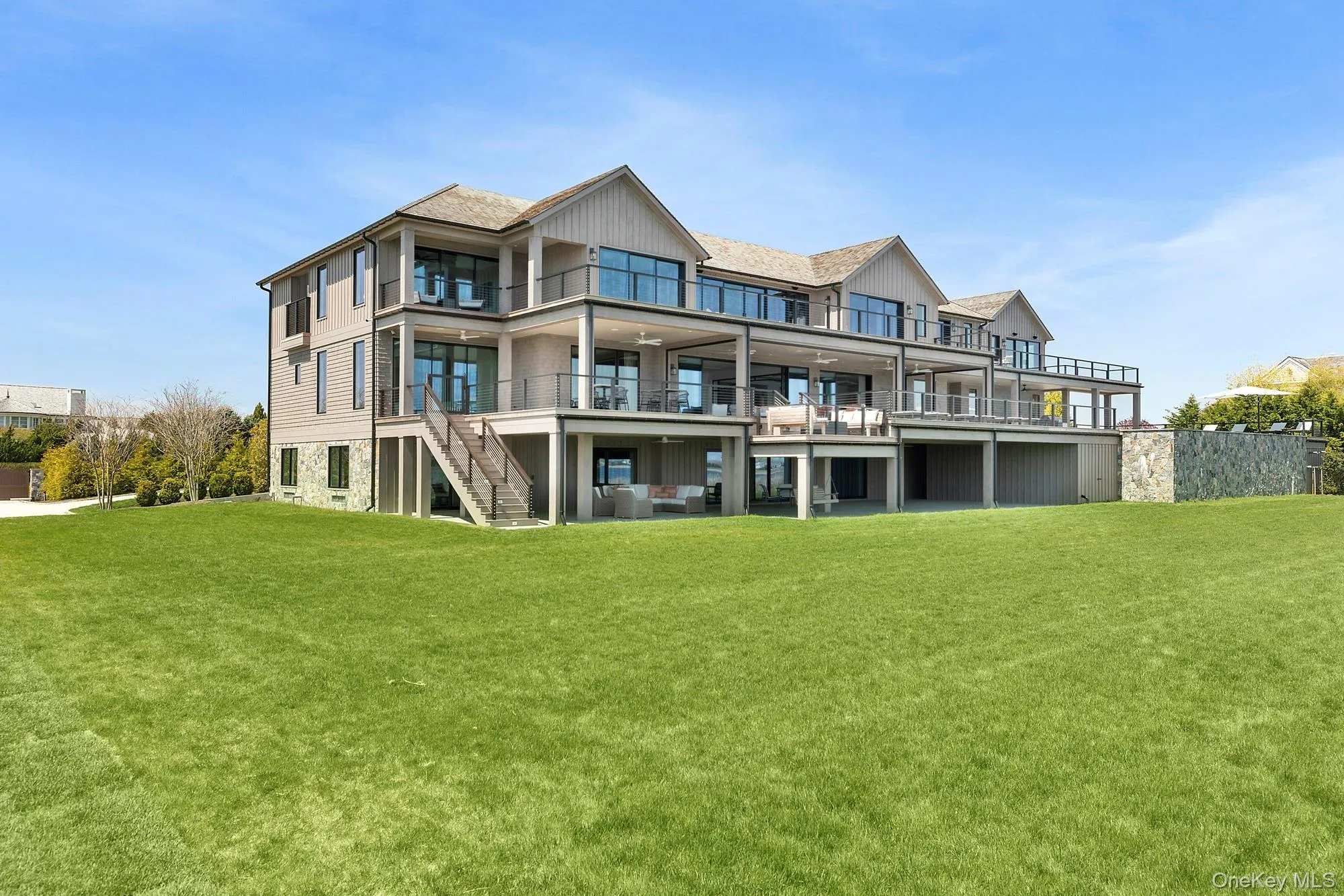 Rear view of property with a balcony, a lawn, and stairway Rear view of property with a balcony, a lawn, and stairway