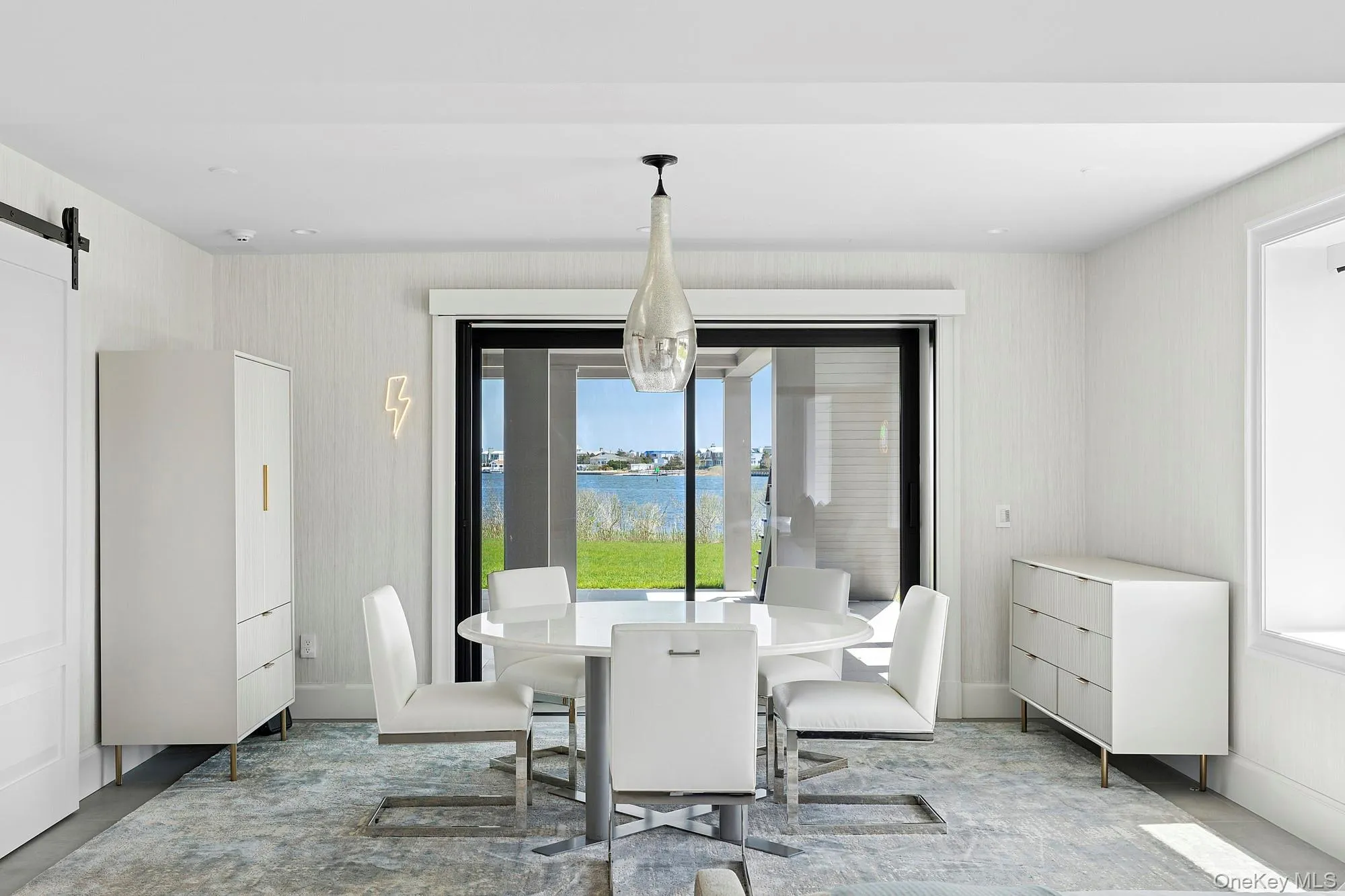 Dining area with a water view, a barn door, and wallpapered walls Dining area with a water view, a barn door, and wallpapered walls