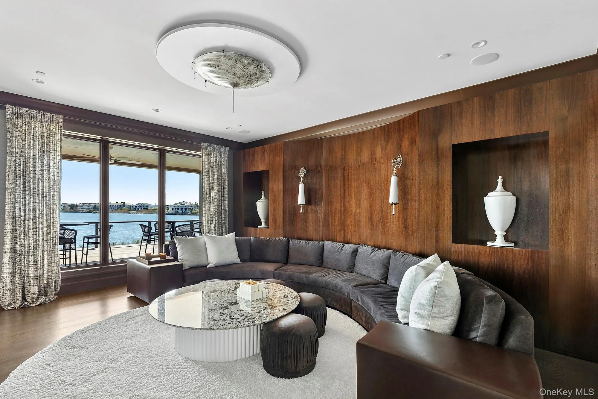 Living area featuring wood walls, a water view, and wood finished floors Living area featuring wood walls, a water view, and wood finished floors