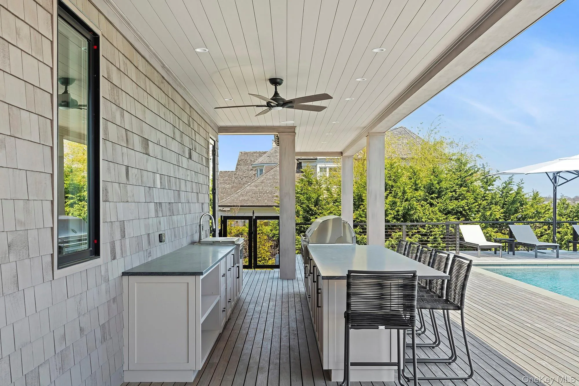 Wooden deck featuring grilling area, a ceiling fan, an outdoor pool, and a sink Wooden deck featuring grilling area, a ceiling fan, an outdoor pool, and a sink