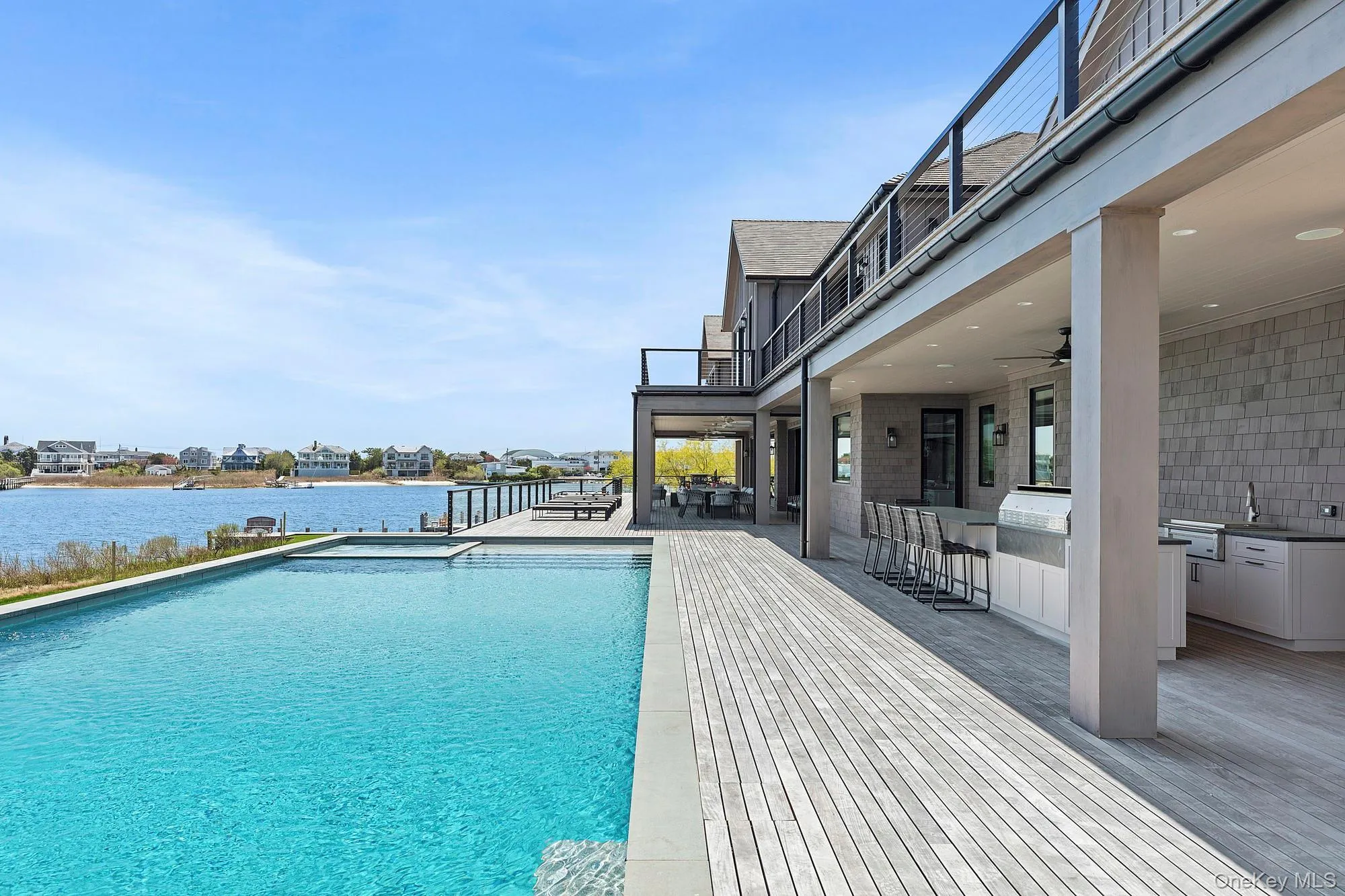 Swimming pool with area for grilling, a water view, a ceiling fan, a patio area, and a sink Swimming pool with area for grilling, a water view, a ceiling fan, a patio area, and a sink