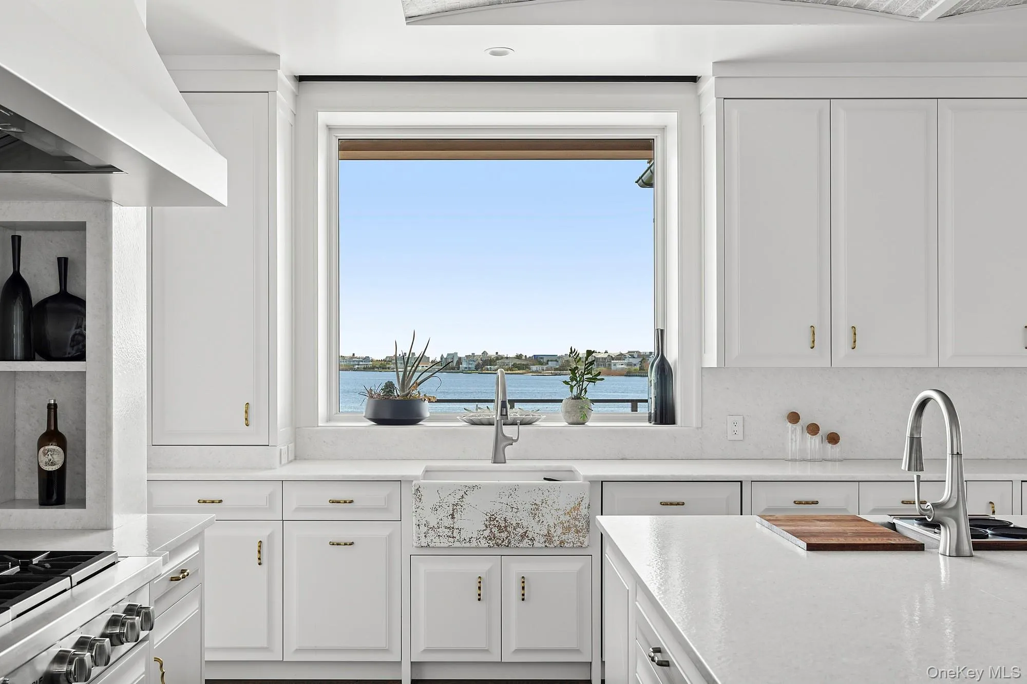 Kitchen featuring a sink, white cabinetry, wall chimney exhaust hood, a water view, and range Kitchen featuring a sink, white cabinetry, wall chimney exhaust hood, a water view, and range