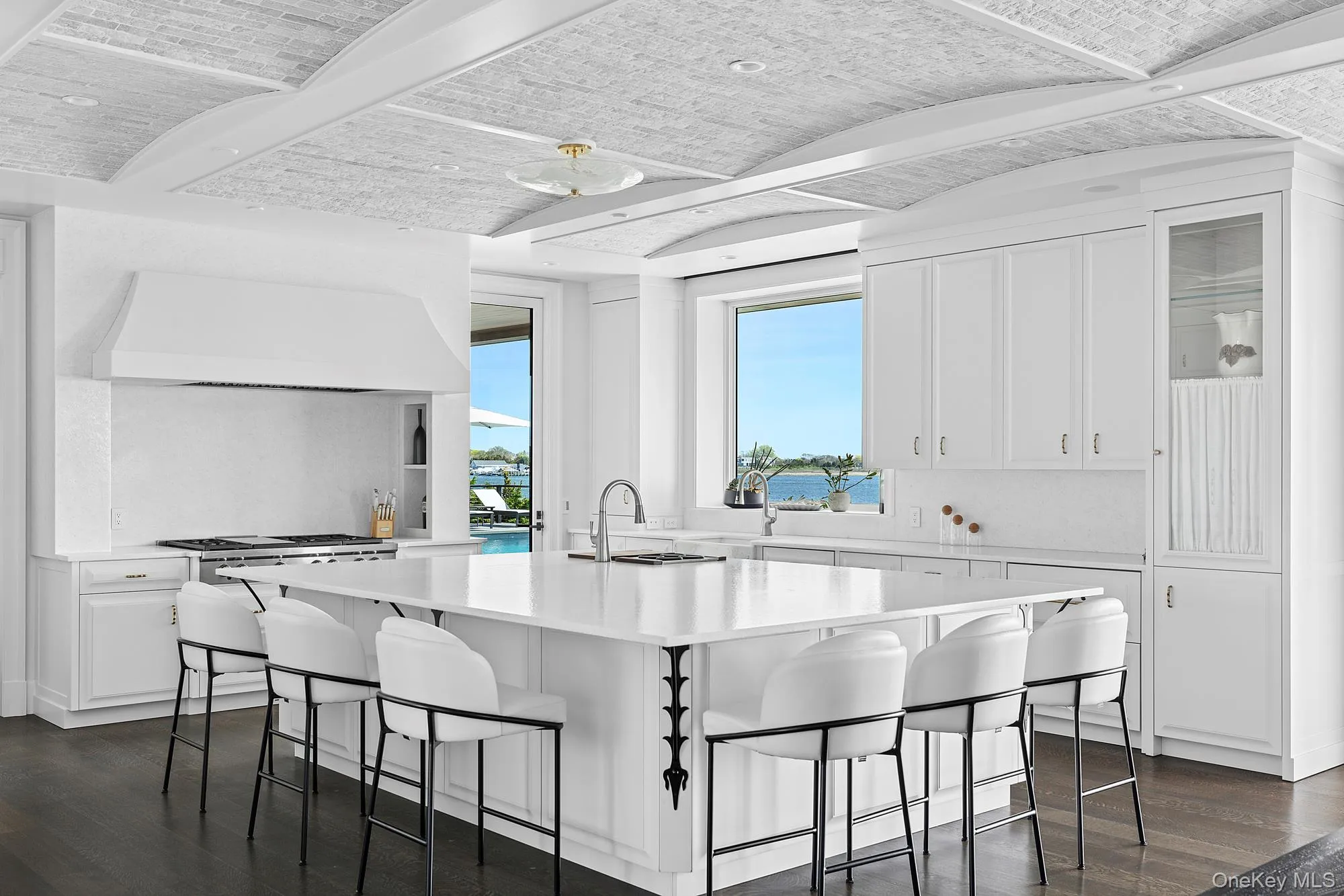 Kitchen with dark wood-style floors, white cabinetry, light countertops, a kitchen breakfast bar, and brick ceiling Kitchen with dark wood-style floors, white cabinetry, light countertops, a kitchen breakfast bar, and brick ceiling