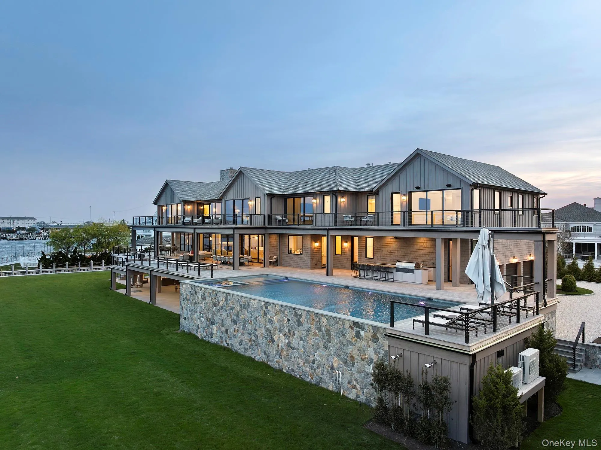 Back of property at dusk with a balcony, a yard, an outdoor living space, an outdoor pool, and a patio area Back of property at dusk with a balcony, a yard, an outdoor living space, an outdoor pool, and a patio area