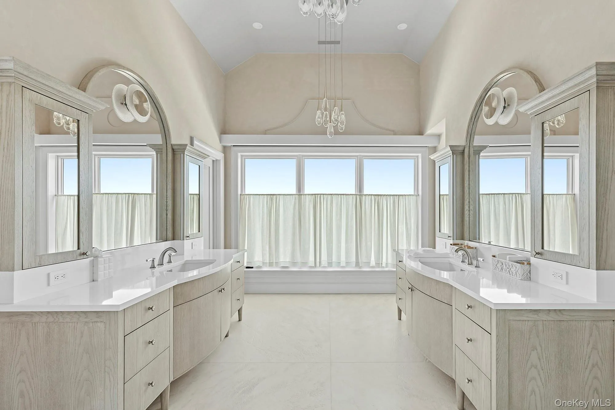 Bathroom featuring a chandelier, two vanities, and high vaulted ceiling Bathroom featuring a chandelier, two vanities, and high vaulted ceiling