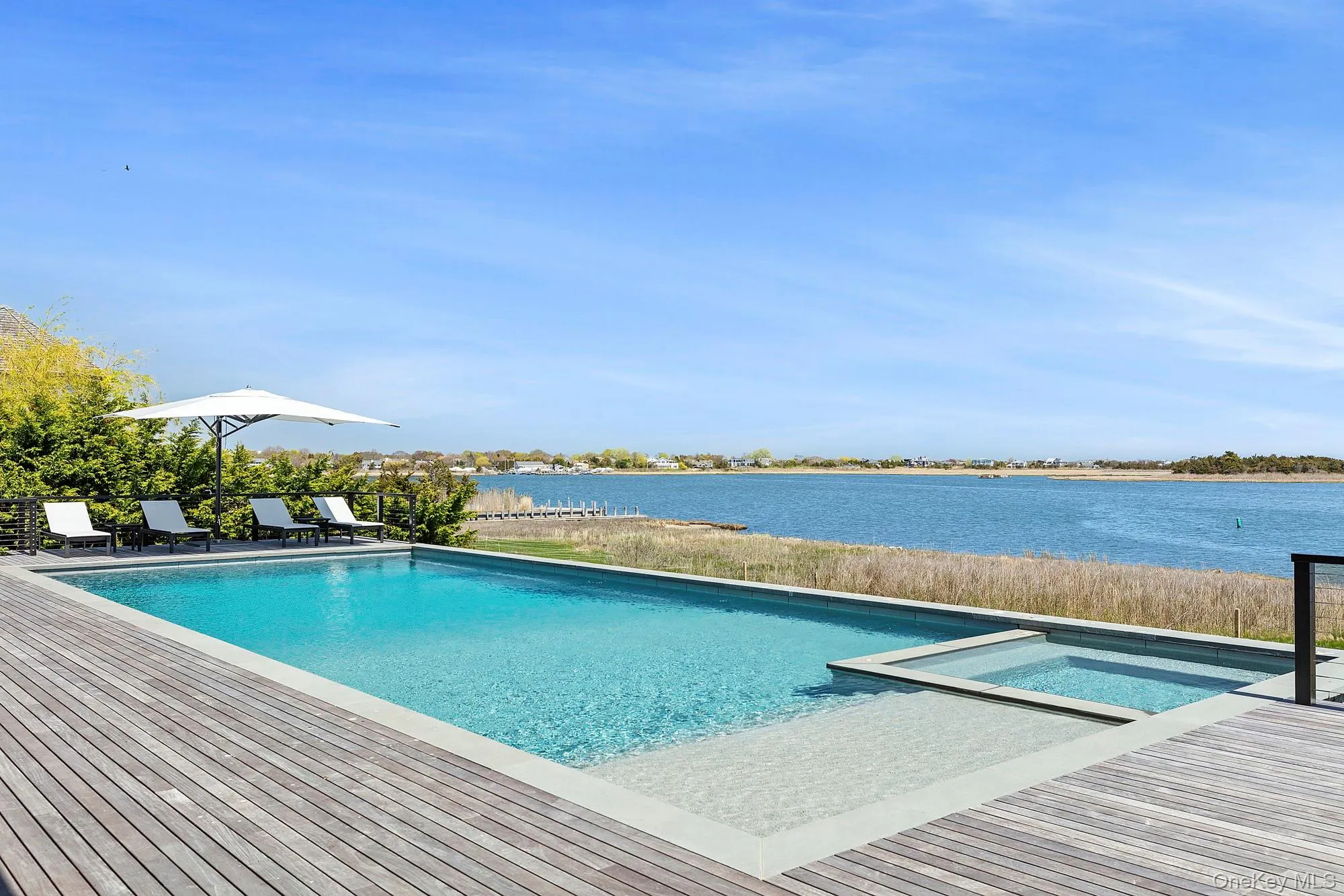 View of swimming pool featuring a water view and a pool with connected hot tub View of swimming pool featuring a water view and a pool with connected hot tub