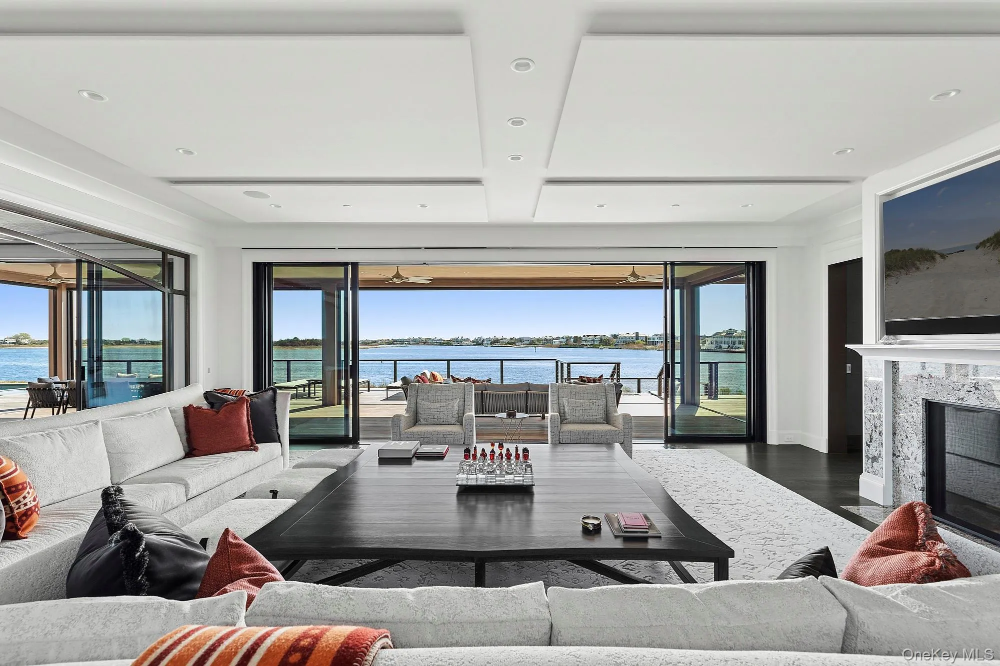 Living area with a water view, a premium fireplace, wood finished floors, plenty of natural light, and recessed lighting Living area with a water view, a premium fireplace, wood finished floors, plenty of natural light, and recessed lighting