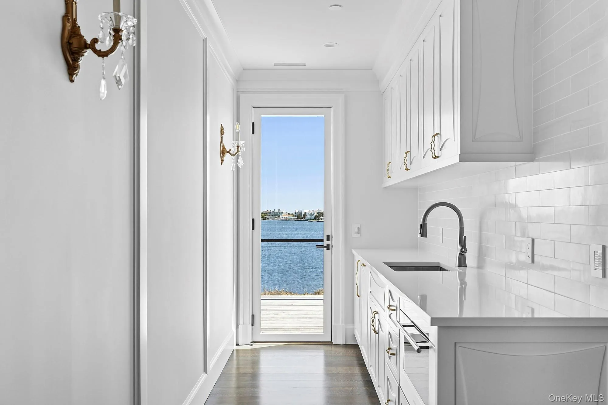 Bar with a sink, decorative backsplash, dark wood-type flooring, and a water view Bar with a sink, decorative backsplash, dark wood-type flooring, and a water view