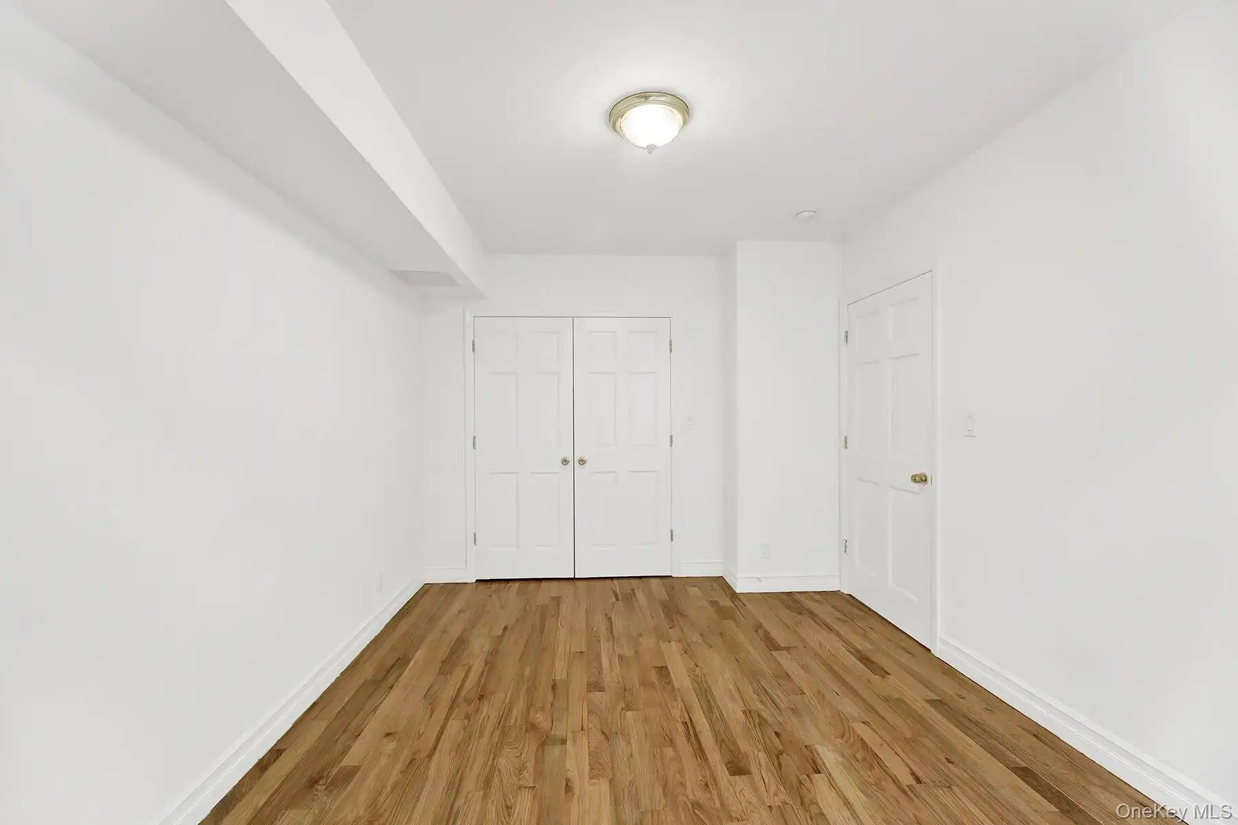 Unfurnished bedroom featuring wood finished floors and a closet Unfurnished bedroom featuring wood finished floors and a closet