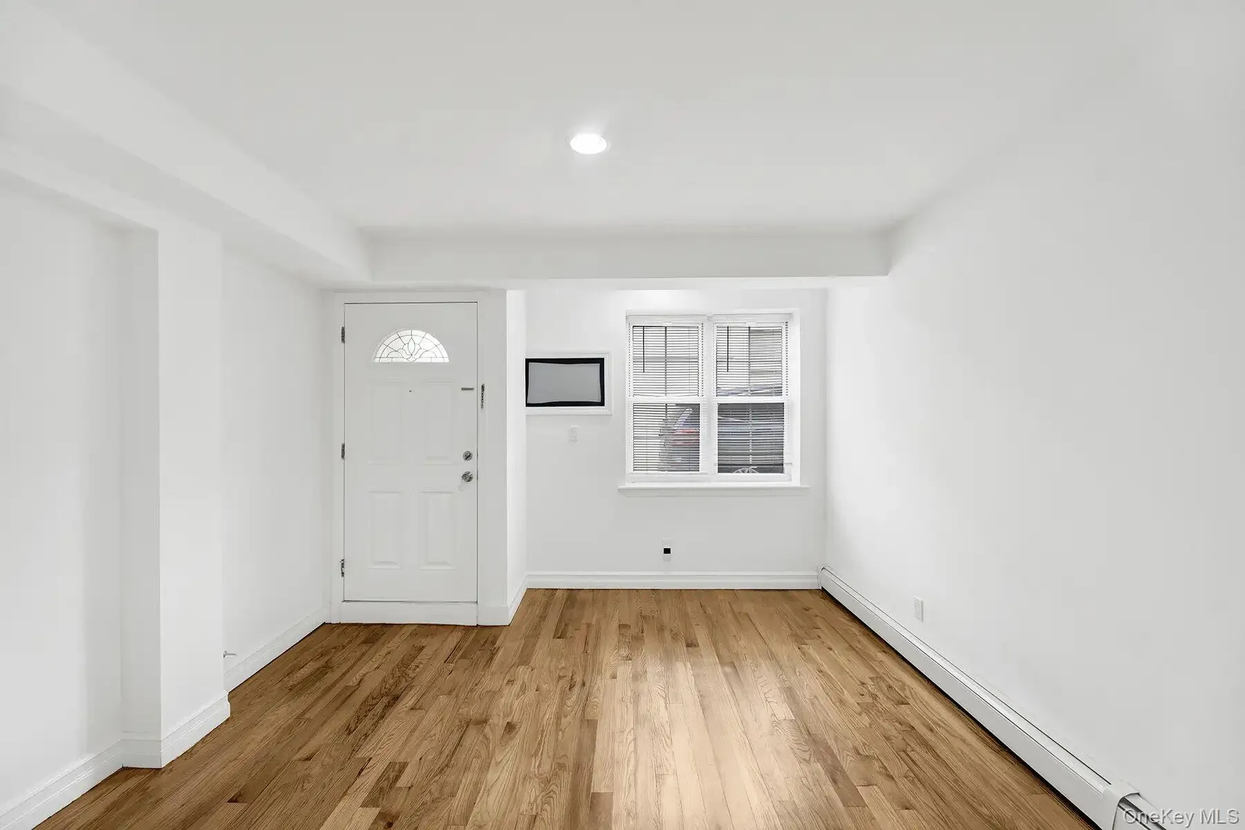 Foyer featuring a baseboard radiator and light wood-type flooring Foyer featuring a baseboard radiator and light wood-type flooring