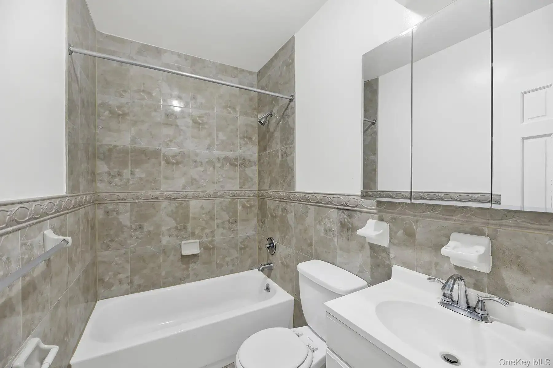 Full bath featuring tile walls, vanity, and shower combination Full bath featuring tile walls, vanity, and shower combination