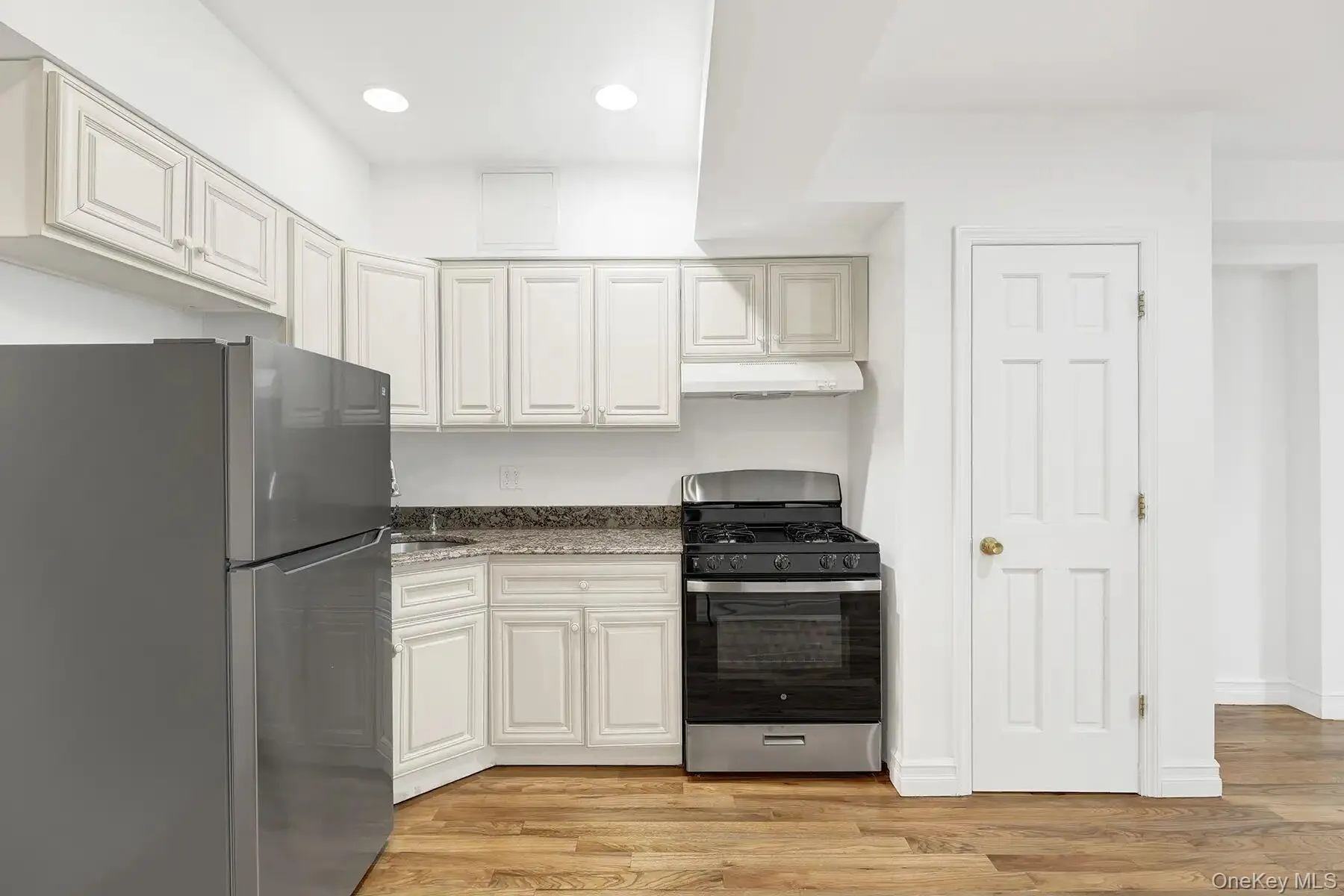 Kitchen featuring stainless steel appliances, light wood-style floors, white cabinetry, dark stone counters, and recessed lighting Kitchen featuring stainless steel appliances, light wood-style floors, white cabinetry, dark stone counters, and recessed lighting
