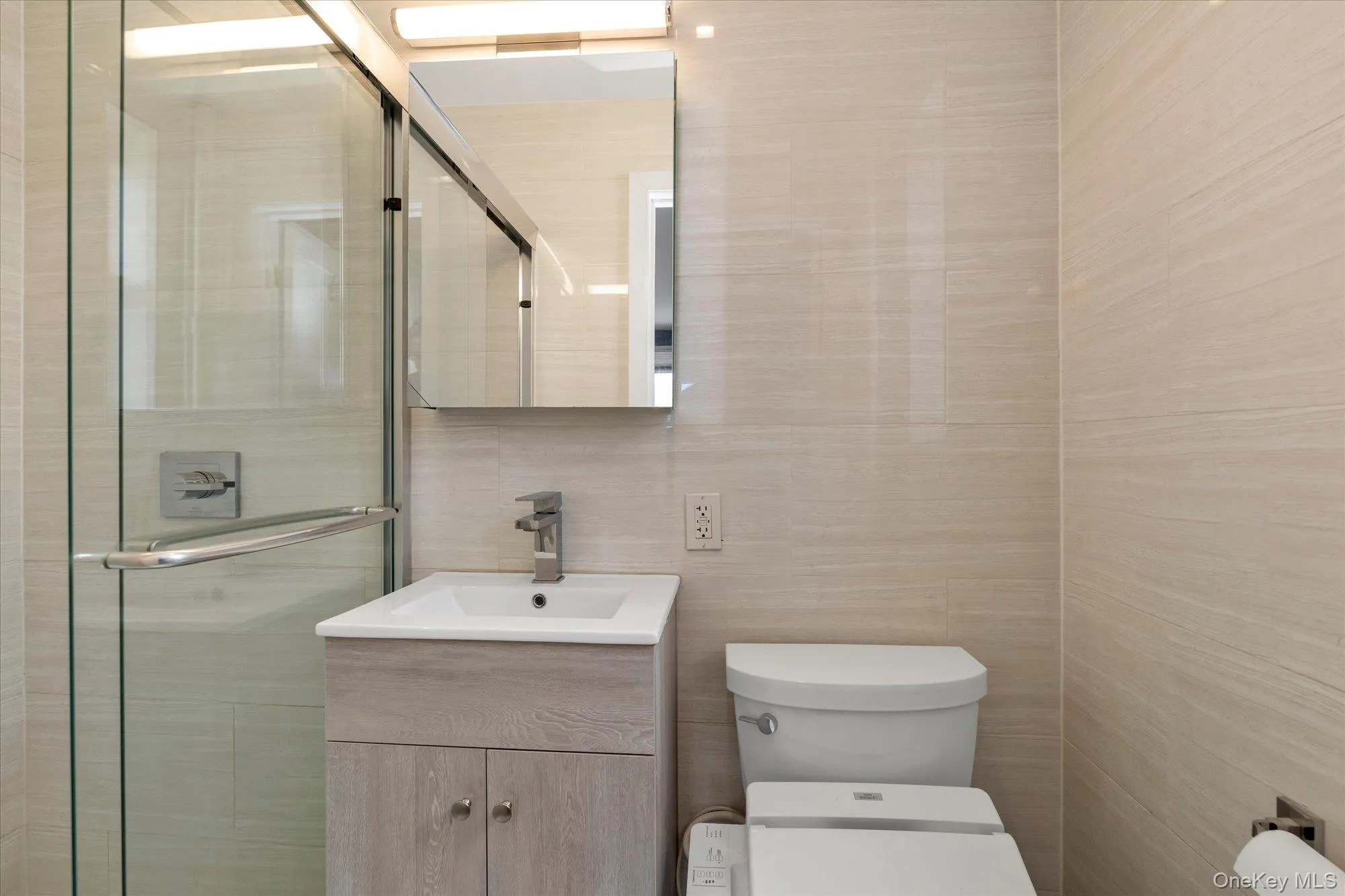 Bathroom with tile walls, vanity, and a shower stall Bathroom with tile walls, vanity, and a shower stall
