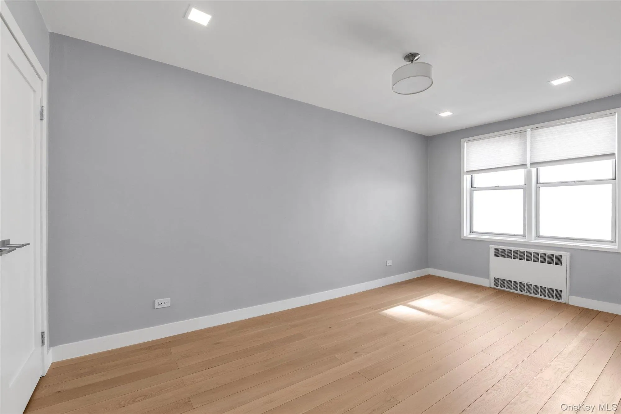 Second bedroom with radiator, light wood-type flooring, recessed lighting Second bedroom with radiator, light wood-type flooring, recessed lighting