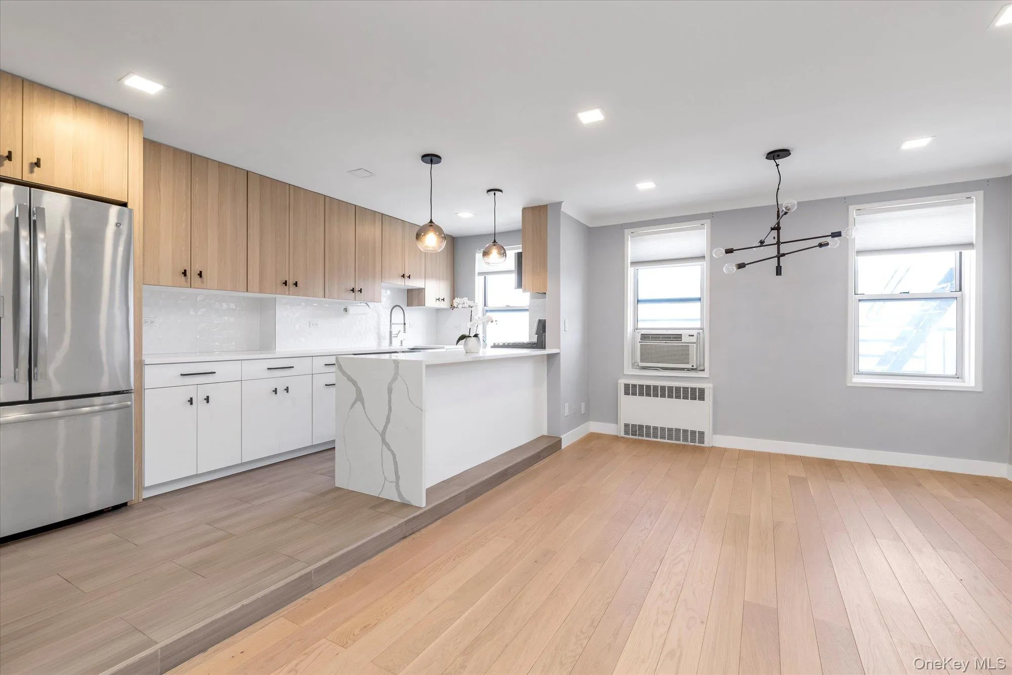 Kitchen featuring freestanding refrigerator, light wood-style floors, radiator, backsplash, pendant lighting, recessed lighting, cooling unit. Kitchen featuring freestanding refrigerator, light wood-style floors, radiator, backsplash, pendant lighting, recessed lighting, cooling unit.