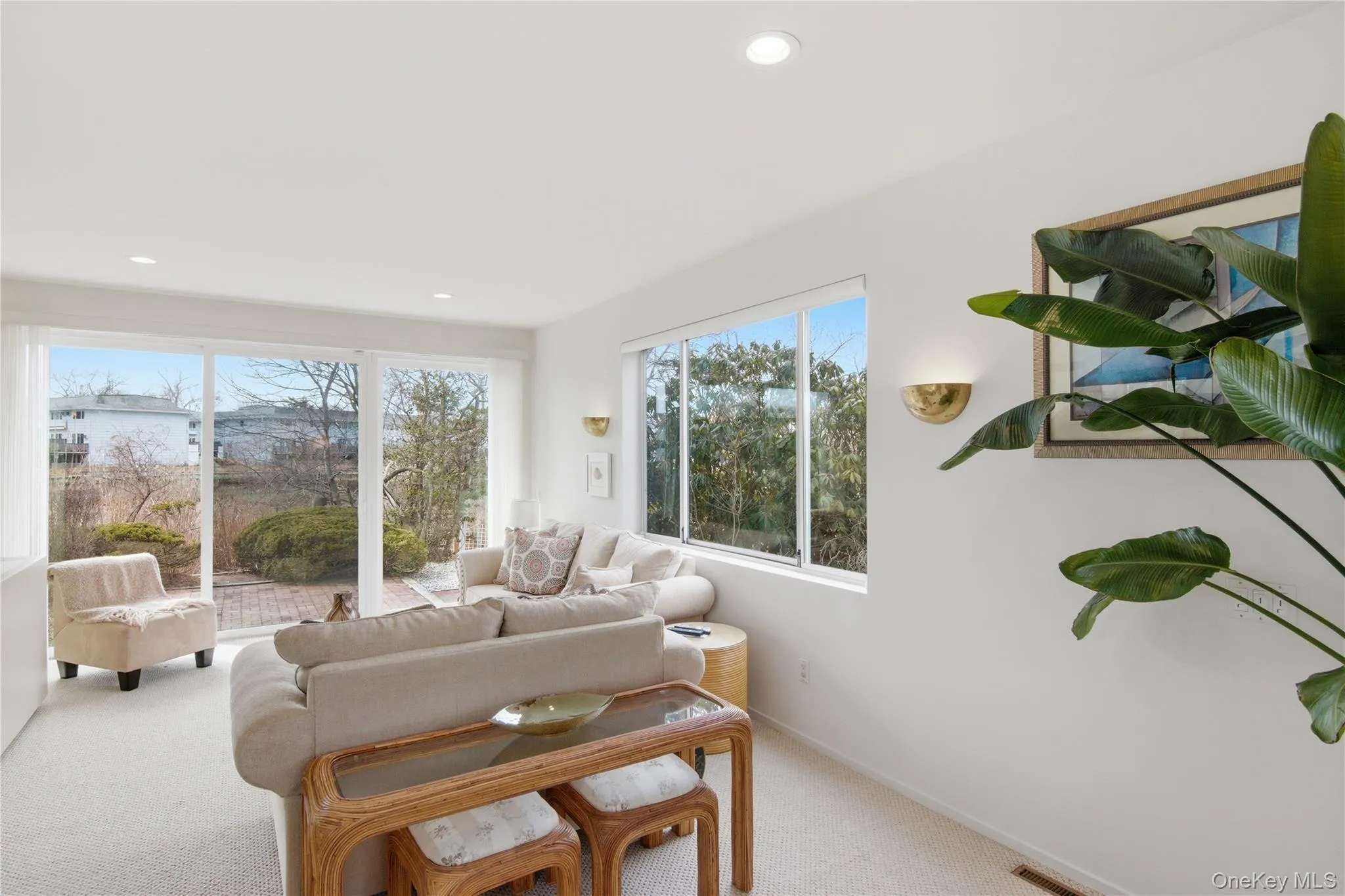Living area with light colored carpet and recessed lighting and sliders that go out to the patio and water Living area with light colored carpet and recessed lighting and sliders that go out to the patio and water