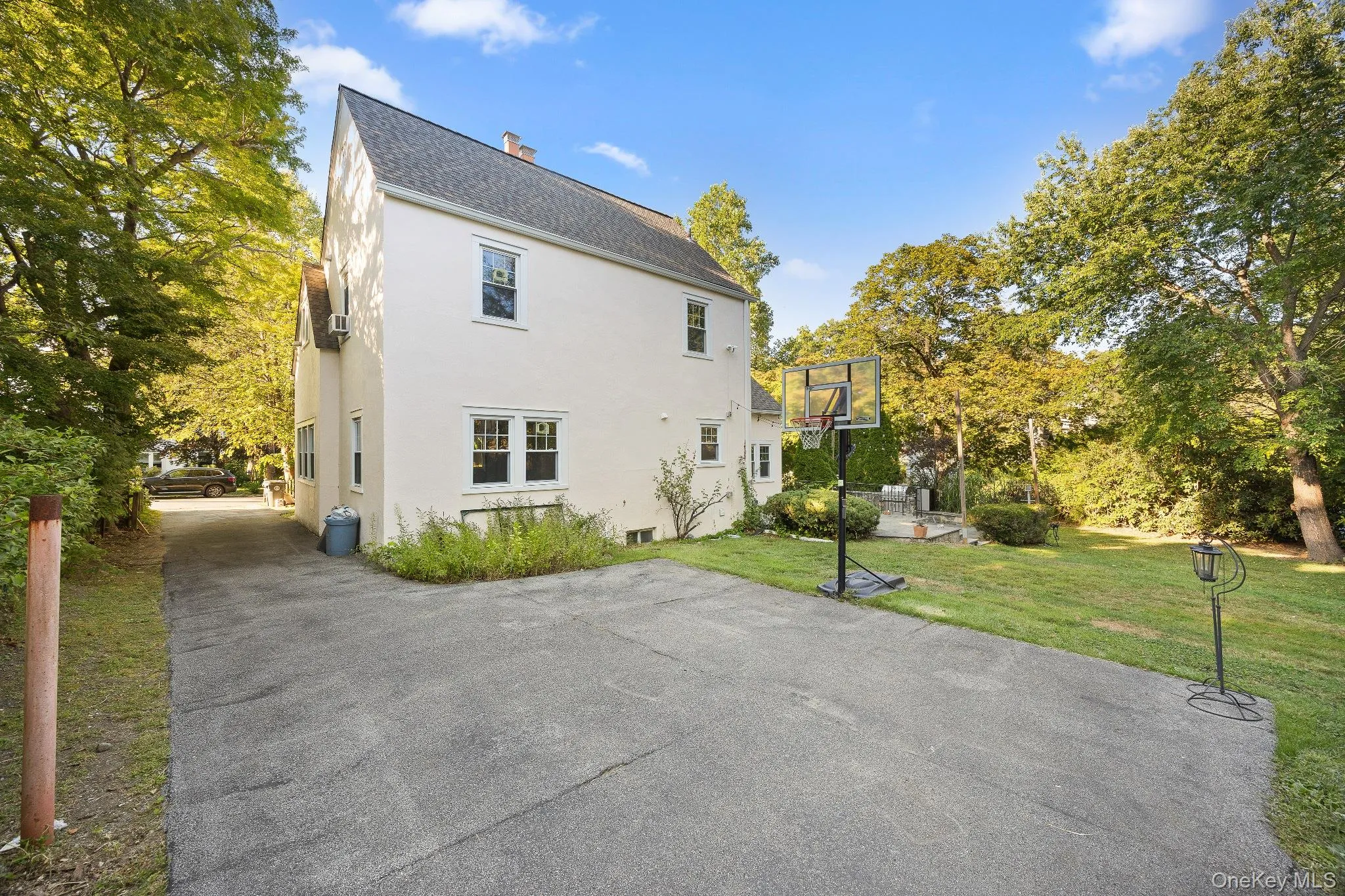 Rear view of property with roof with shingles, a chimney, basketball hoop, a lawn, and stucco siding Rear view of property with roof with shingles, a chimney, basketball hoop, a lawn, and stucco siding