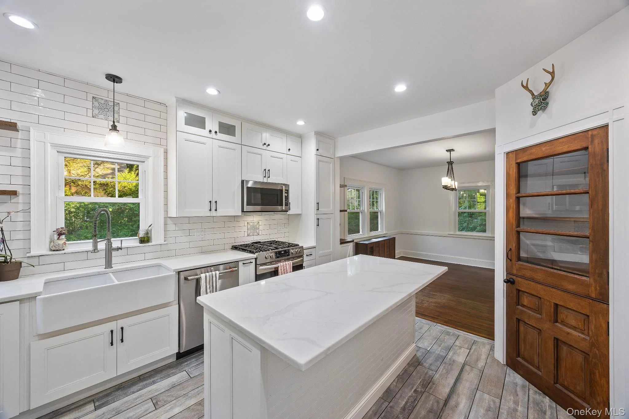 Kitchen with pendant lighting, light stone counters, white cabinets, light wood-style floors, and recessed lighting Kitchen with pendant lighting, light stone counters, white cabinets, light wood-style floors, and recessed lighting