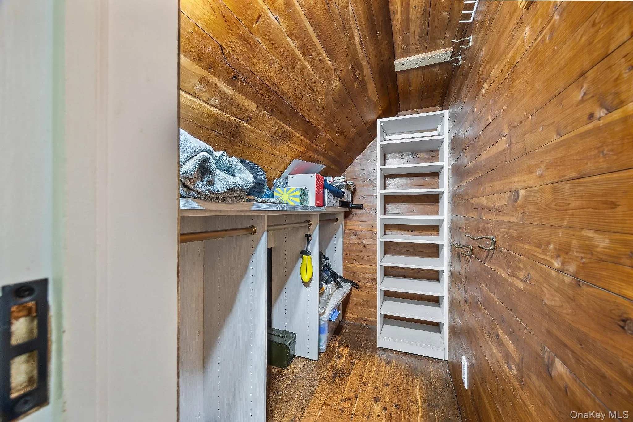 Walk in closet featuring dark wood-type flooring and vaulted ceiling Walk in closet featuring dark wood-type flooring and vaulted ceiling