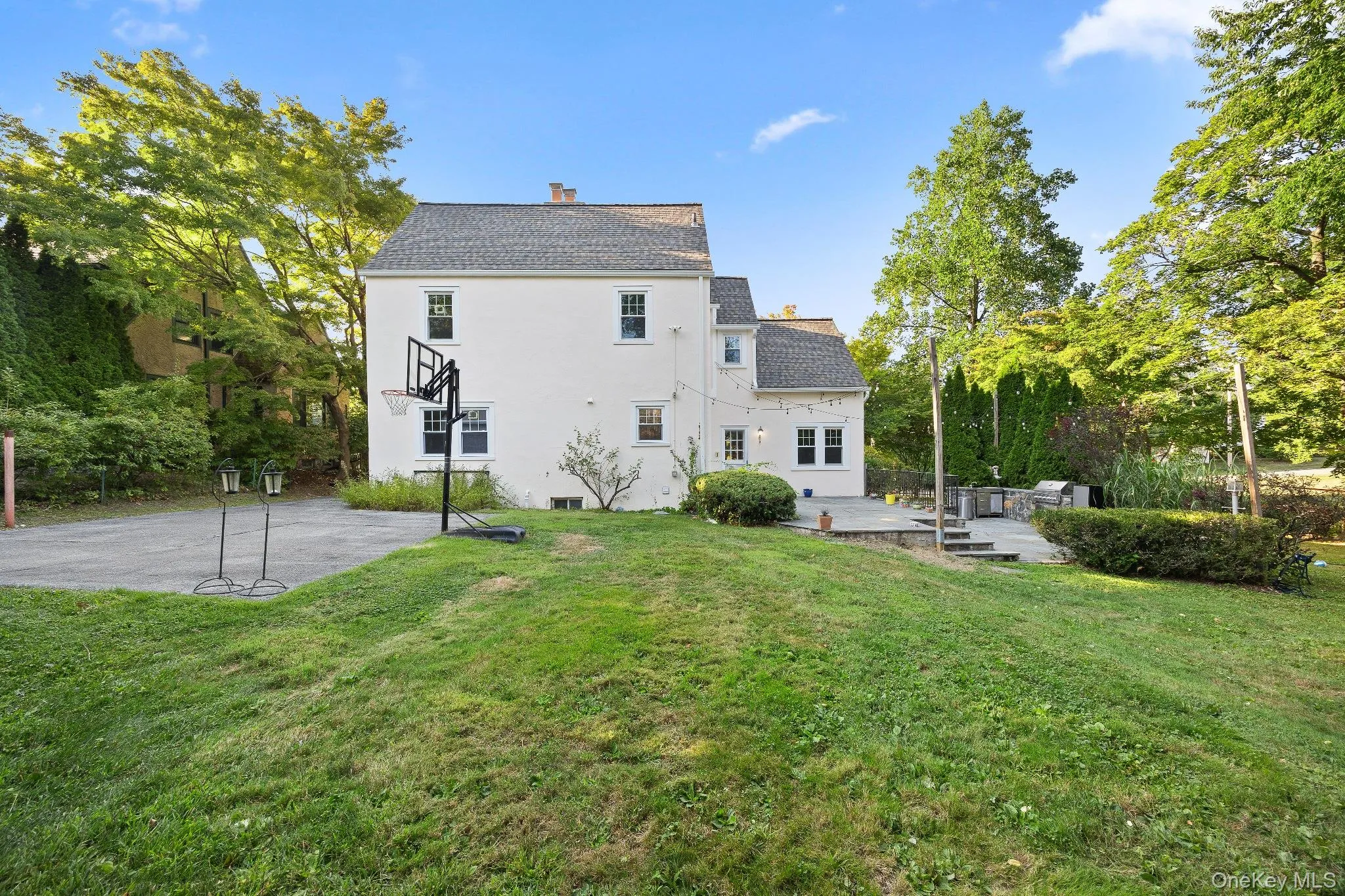 Rear view of house with a lawn, a chimney, roof with shingles, stucco siding, and a deck Rear view of house with a lawn, a chimney, roof with shingles, stucco siding, and a deck