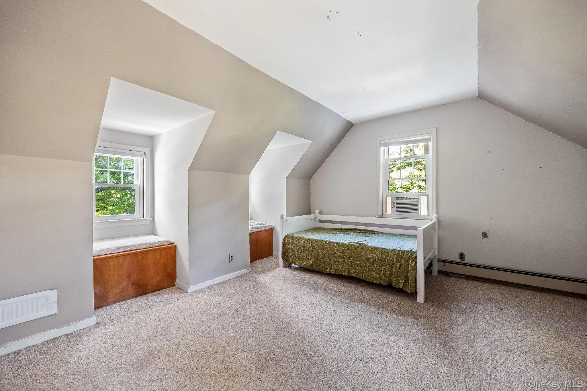 Unfurnished bedroom featuring light colored carpet, lofted ceiling, and baseboard heating Unfurnished bedroom featuring light colored carpet, lofted ceiling, and baseboard heating
