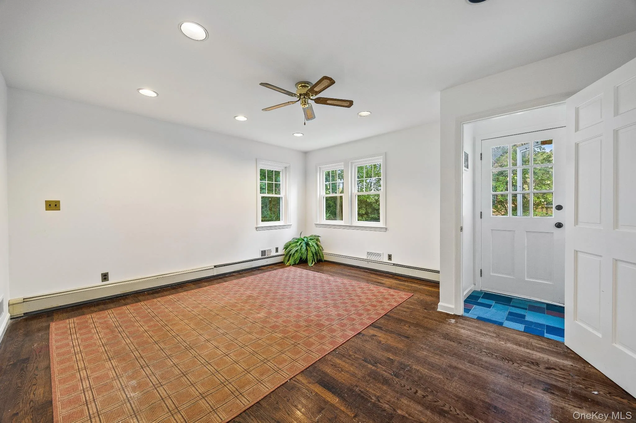 Unfurnished room with healthy amount of natural light, recessed lighting, baseboard heating, and dark wood-style flooring Unfurnished room with healthy amount of natural light, recessed lighting, baseboard heating, and dark wood-style flooring