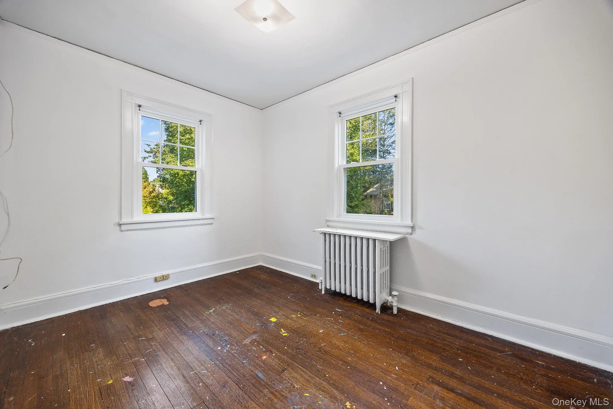 Unfurnished room featuring dark wood-type flooring and radiator Unfurnished room featuring dark wood-type flooring and radiator