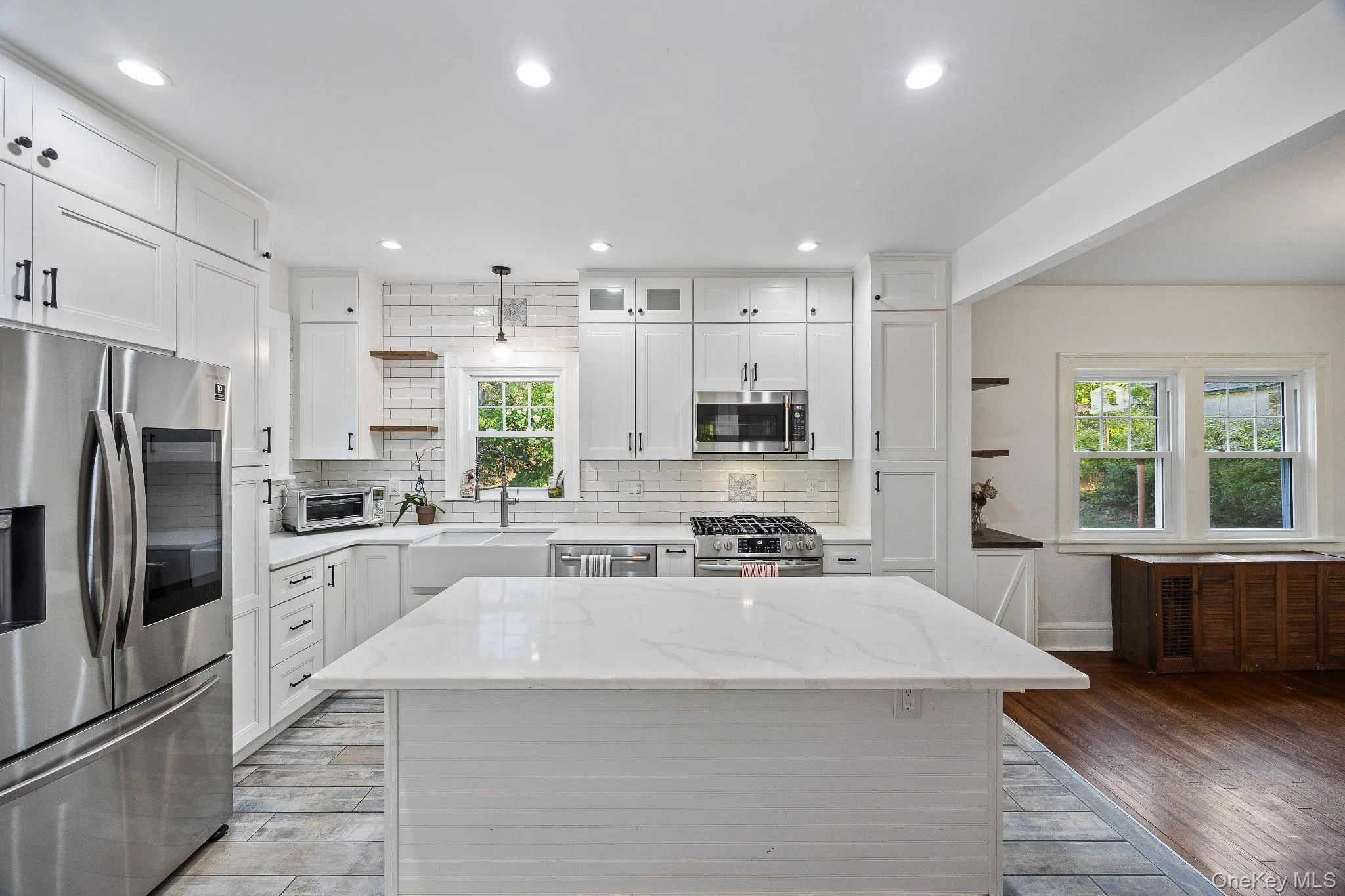 Kitchen with open shelves, light stone countertops, white cabinets, appliances with stainless steel finishes, and light wood finished floors Kitchen with open shelves, light stone countertops, white cabinets, appliances with stainless steel finishes, and light wood finished floors