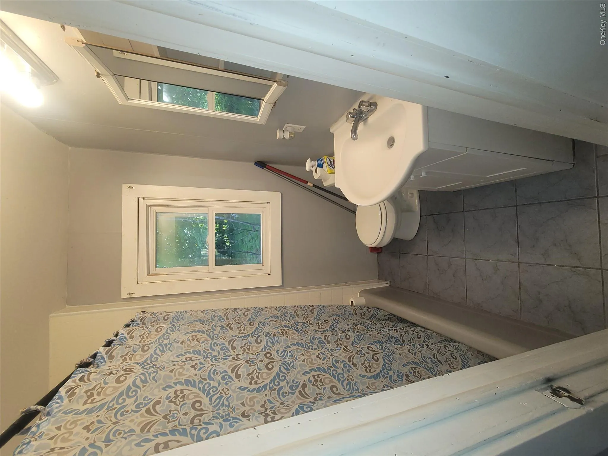 Bathroom featuring a white vanity with integrated sink, white toilet, and a bathtub with a shower Bathroom featuring a white vanity with integrated sink, white toilet, and a bathtub with a shower