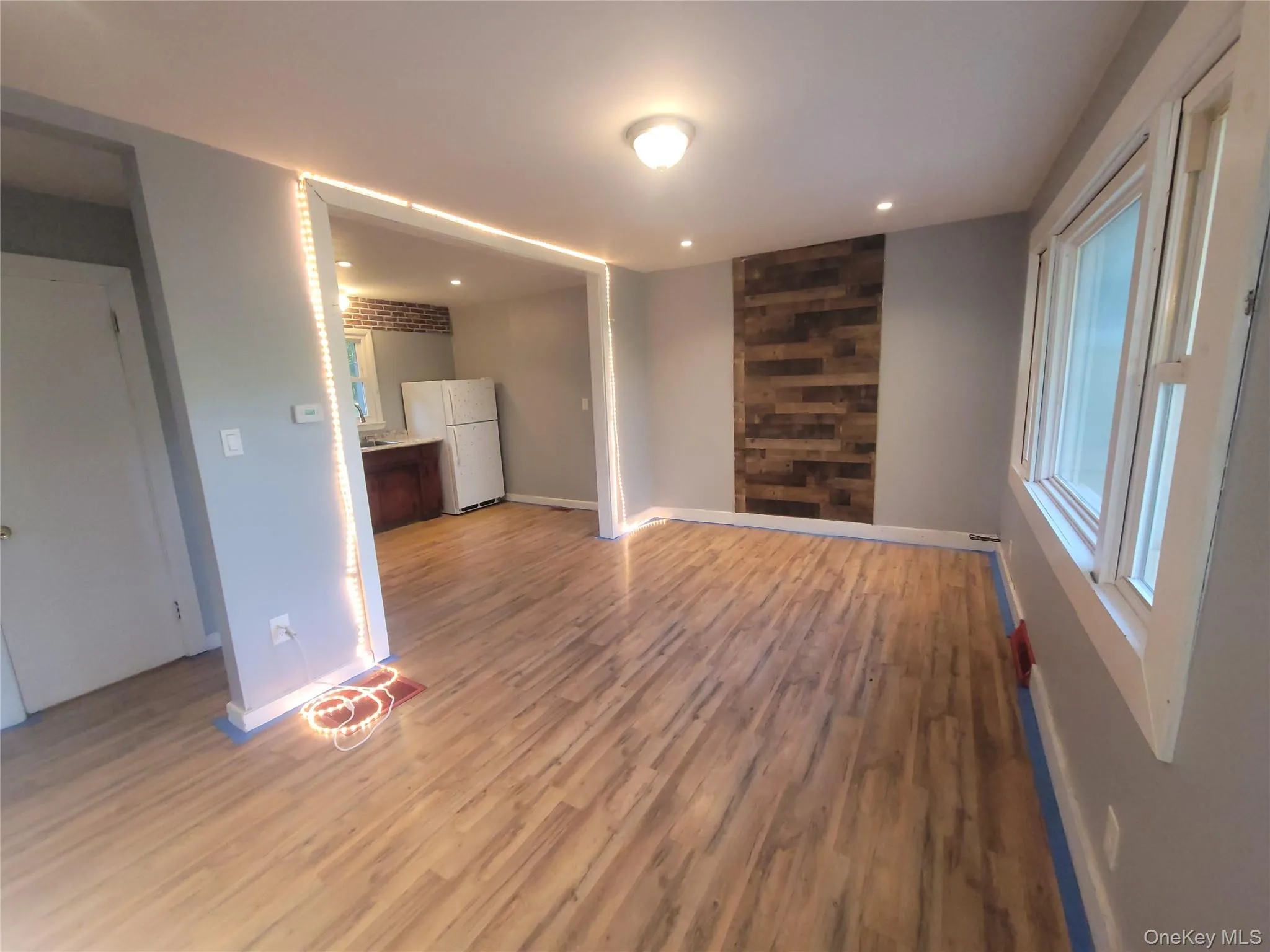 Spacious room featuring wood-finish flooring and a textured accent wall Spacious room featuring wood-finish flooring and a textured accent wall