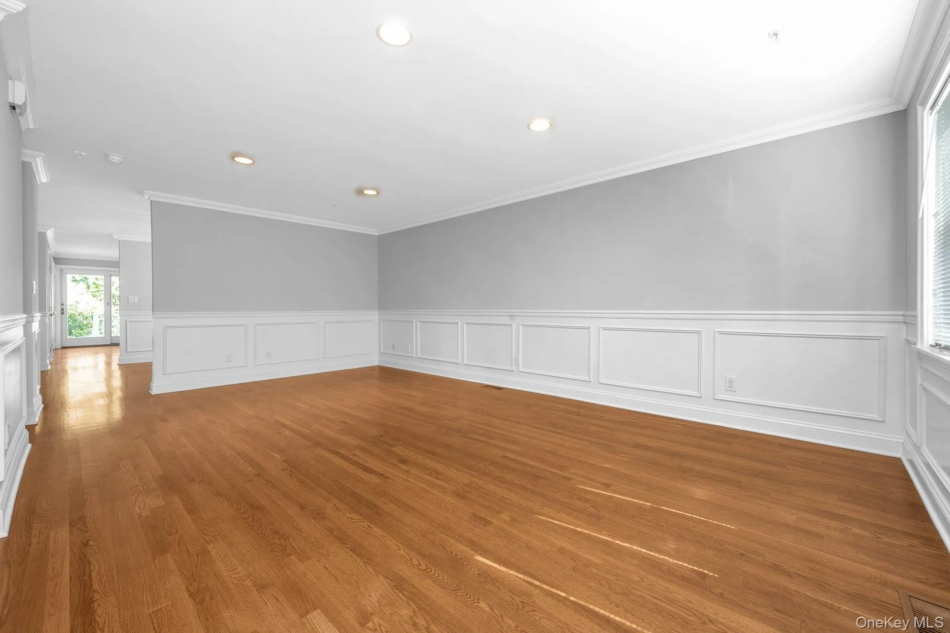 Unfurnished room featuring wainscoting, ornamental molding, recessed lighting, light wood-style floors, and a decorative wall Unfurnished room featuring wainscoting, ornamental molding, recessed lighting, light wood-style floors, and a decorative wall