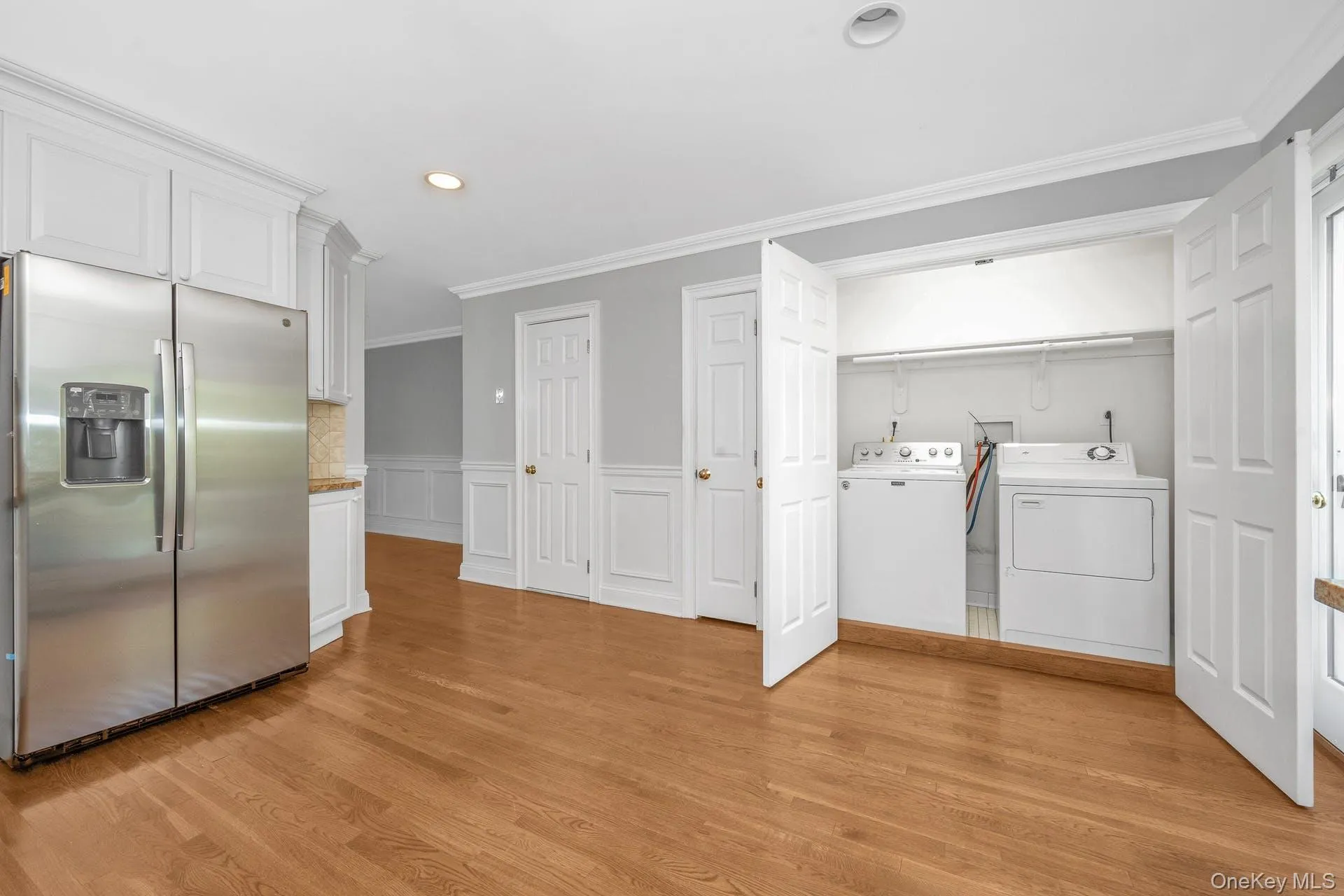 Washroom featuring independent washer and dryer, ornamental molding, recessed lighting, light wood-style floors, and a wainscoted wall Washroom featuring independent washer and dryer, ornamental molding, recessed lighting, light wood-style floors, and a wainscoted wall