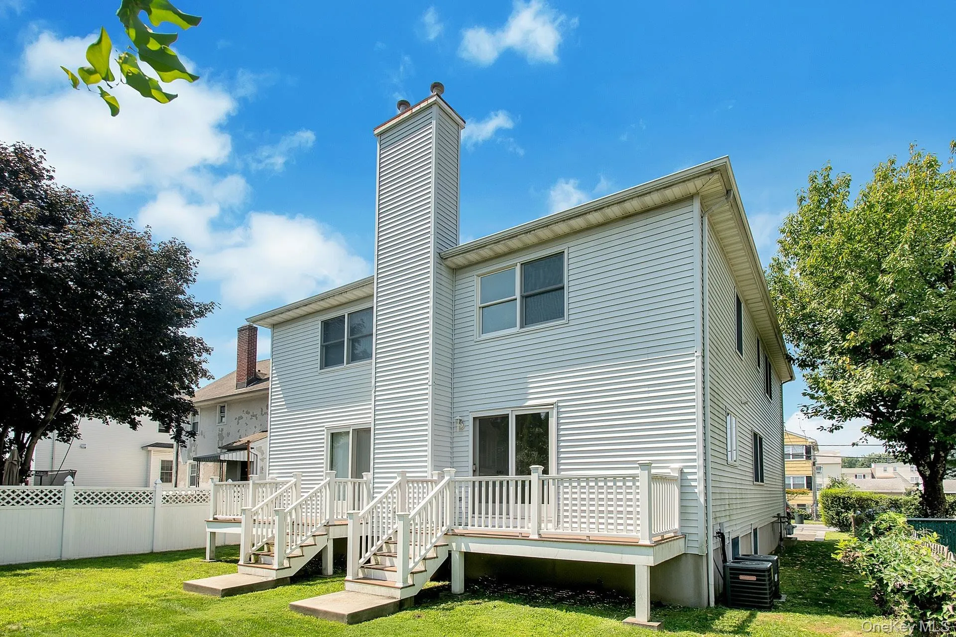 Rear view of property featuring a chimney, a wooden deck, and stairway Rear view of property featuring a chimney, a wooden deck, and stairway