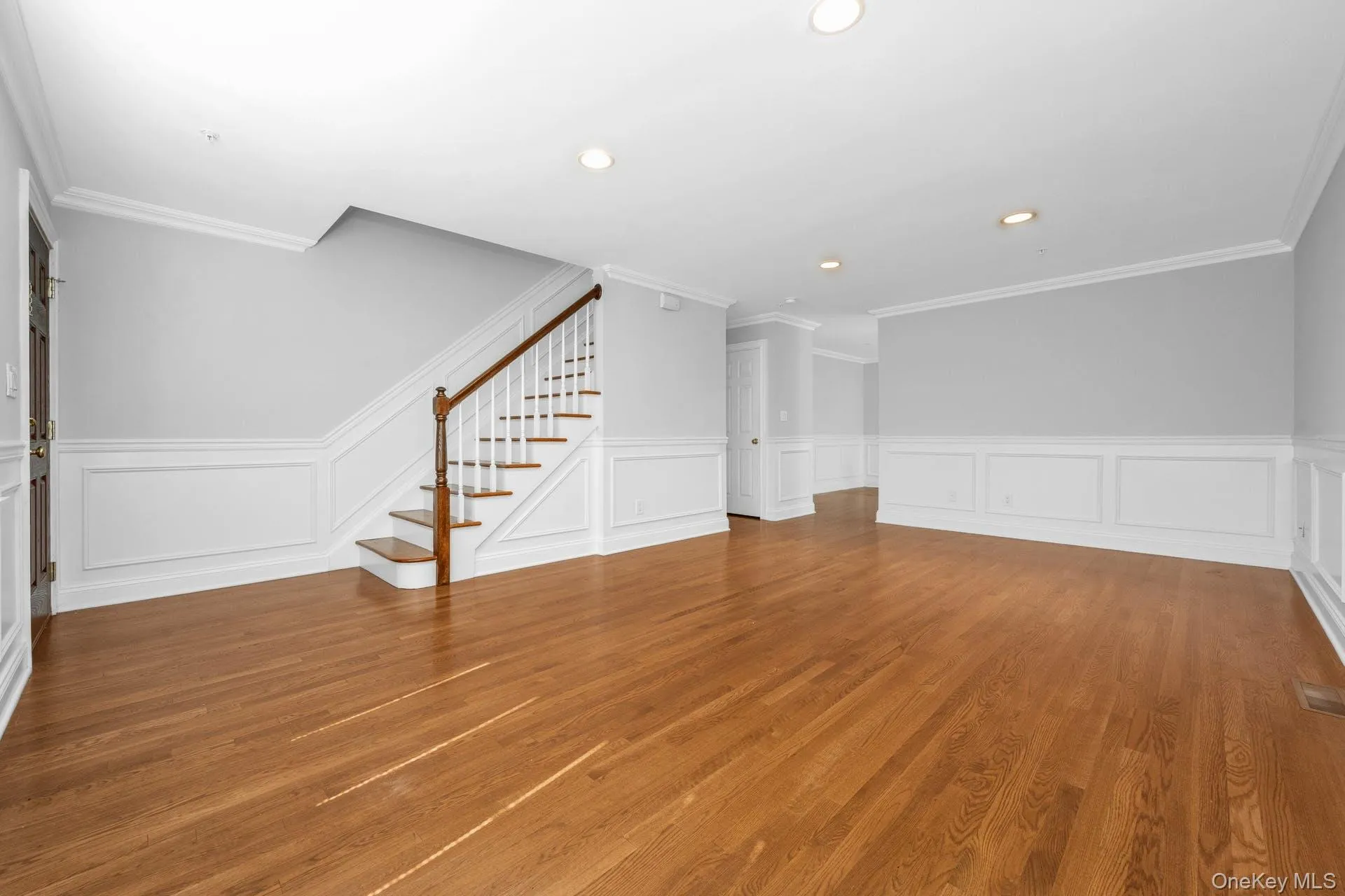 Unfurnished living room with stairway, a wainscoted wall, a decorative wall, recessed lighting, and wood finished floors Unfurnished living room with stairway, a wainscoted wall, a decorative wall, recessed lighting, and wood finished floors