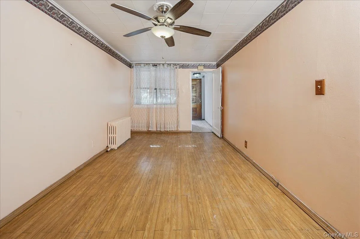 Family room featuring light wood-type flooring, radiator, a ceiling fan, and crown molding Family room featuring light wood-type flooring, radiator, a ceiling fan, and crown molding
