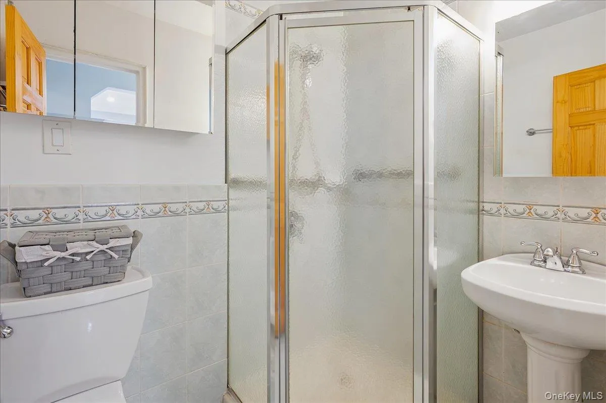 Full primary bathroom with tile walls and a shower stall Full primary bathroom with tile walls and a shower stall