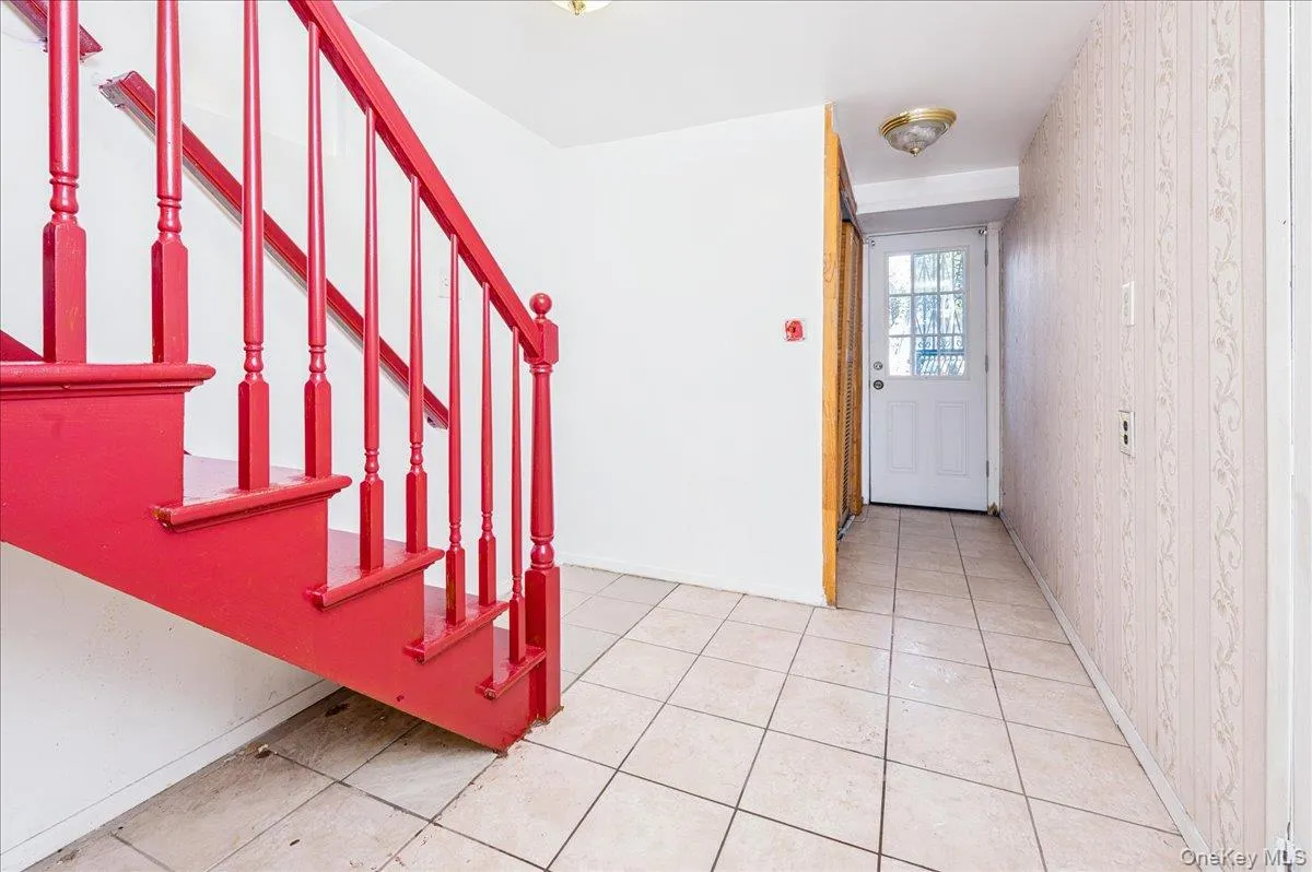 Entrance foyer with light tile patterned floors and wallpapered walls; first floorexit to backyard Entrance foyer with light tile patterned floors and wallpapered walls; first floorexit to backyard