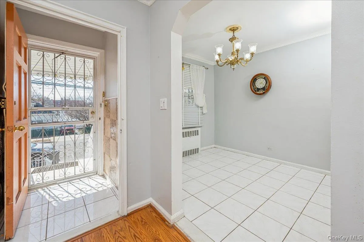 Doorway to outside with a chandelier, ornamental molding, radiator heating unit, finished floors, and arched walkways Doorway to outside with a chandelier, ornamental molding, radiator heating unit, finished floors, and arched walkways
