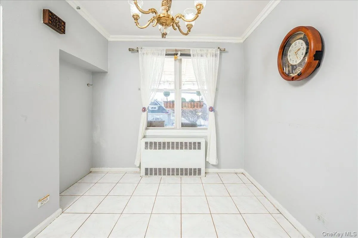 Dining area featuring radiator heating unit, a chandelier, and crown molding Dining area featuring radiator heating unit, a chandelier, and crown molding