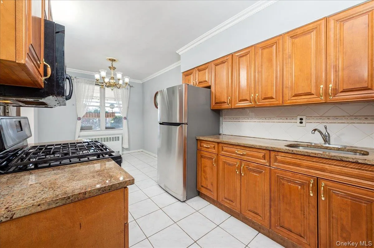 Kitchen featuring wood finish cabinets, light granite countertops, crown molding, stainless steel appliances, and decorative backsplash Kitchen featuring wood finish cabinets, light granite countertops, crown molding, stainless steel appliances, and decorative backsplash