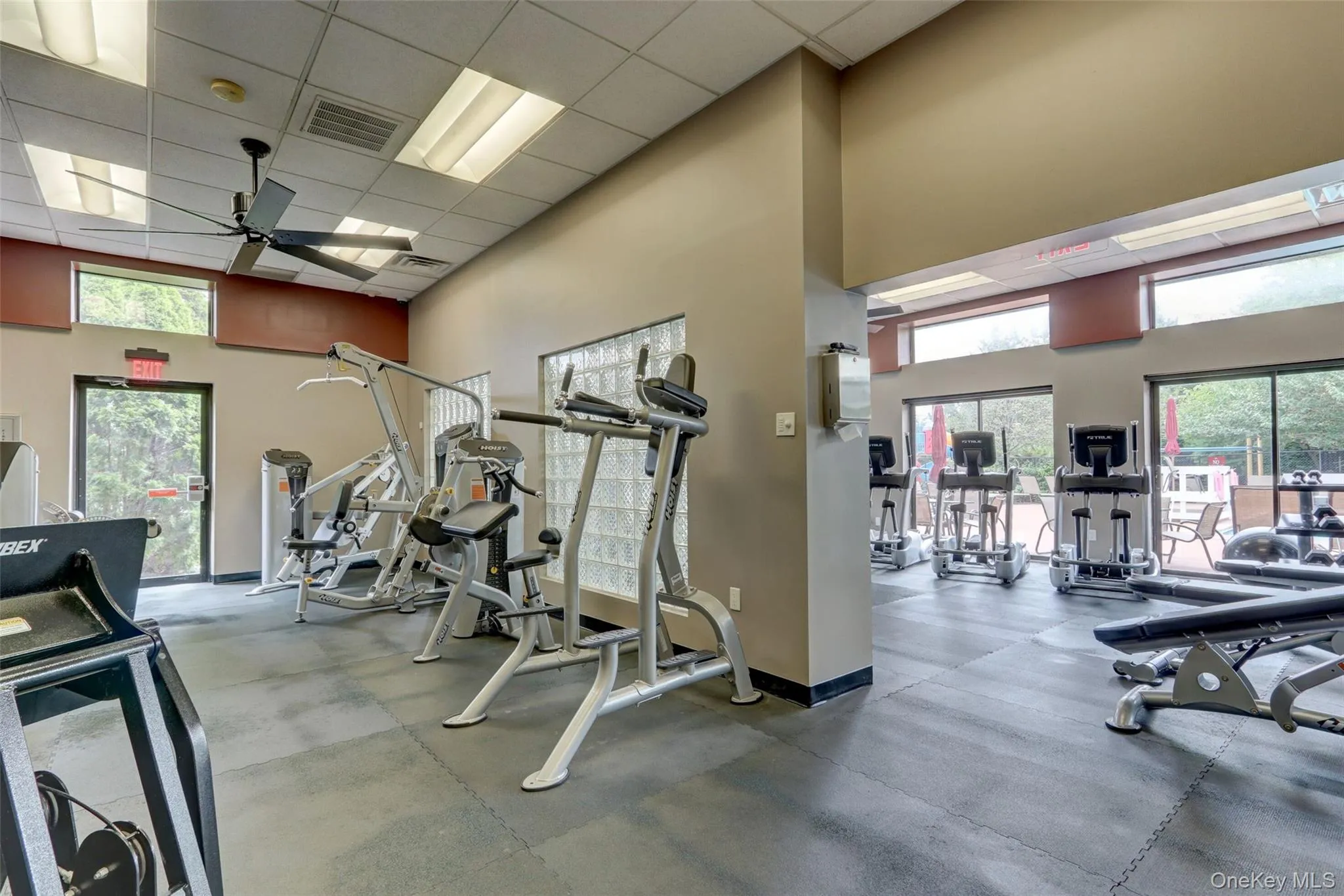 Gym featuring a paneled ceiling, ceiling fan, and a high ceiling Gym featuring a paneled ceiling, ceiling fan, and a high ceiling