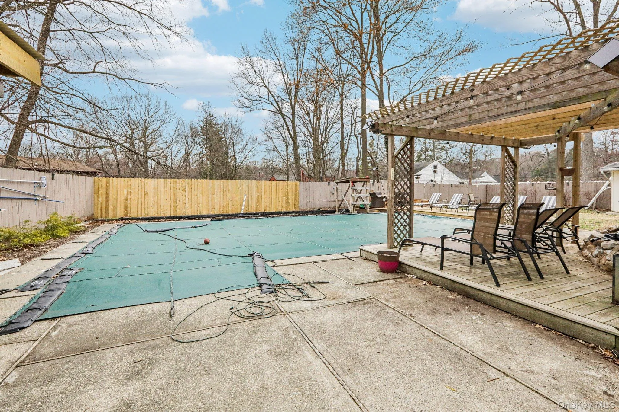 View of pool with a wooden deck, a pergola, a fenced backyard, and patio surround View of pool with a wooden deck, a pergola, a fenced backyard, and patio surround