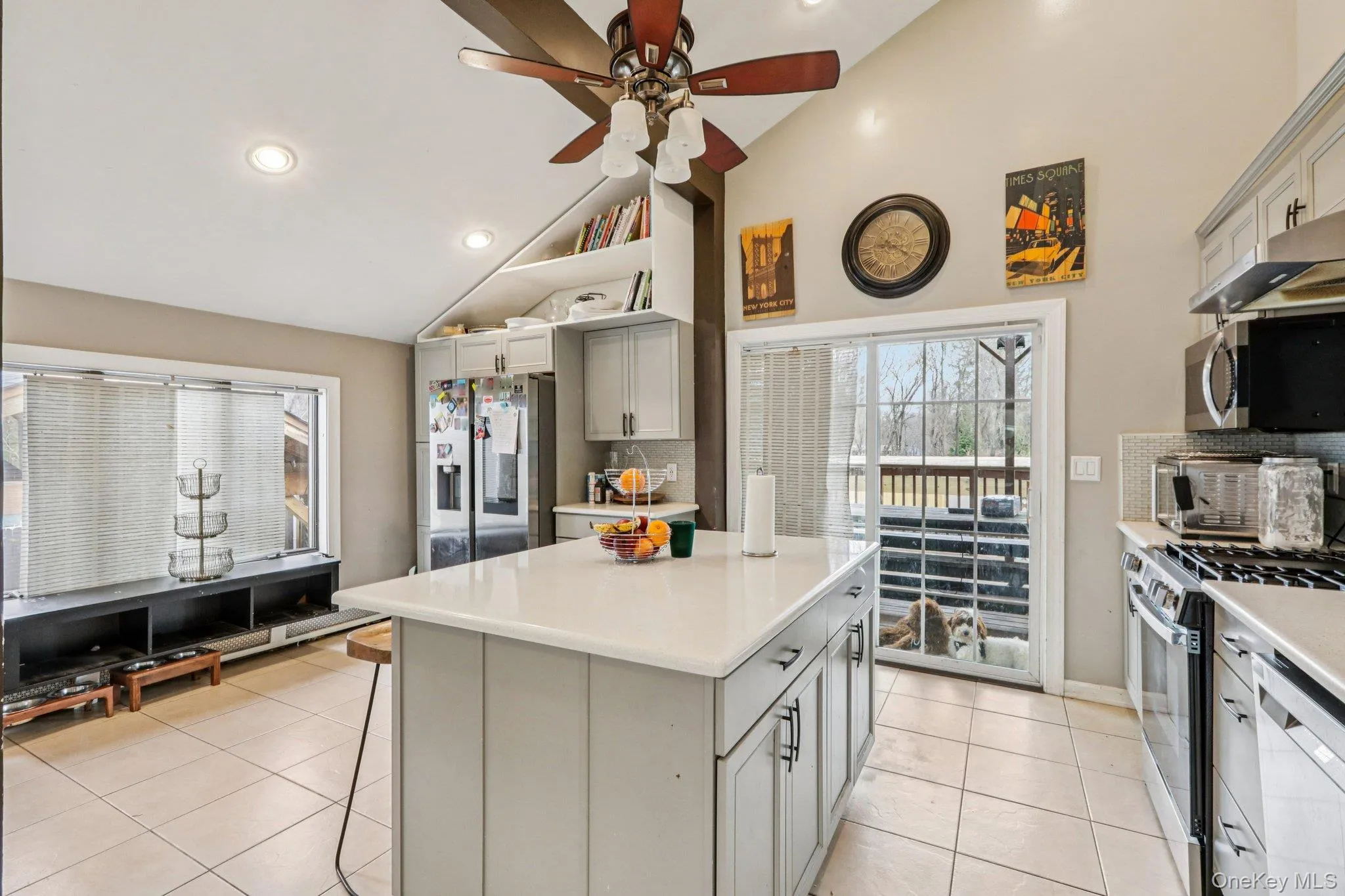 Kitchen with lofted ceiling, a kitchen island, stainless steel appliances, ceiling fan, and light tile patterned floors Kitchen with lofted ceiling, a kitchen island, stainless steel appliances, ceiling fan, and light tile patterned floors