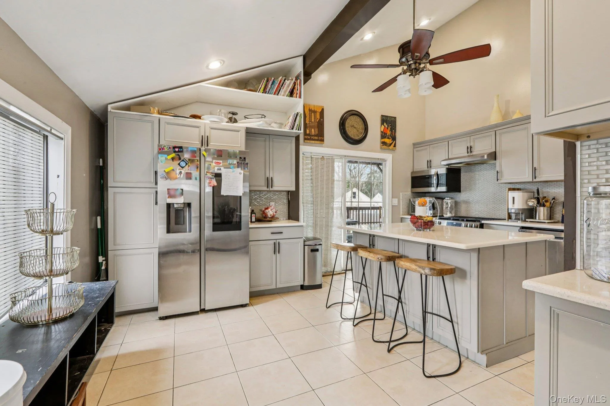 Kitchen with gray cabinetry, stainless steel appliances, a center island, a breakfast bar area, and lofted ceiling Kitchen with gray cabinetry, stainless steel appliances, a center island, a breakfast bar area, and lofted ceiling
