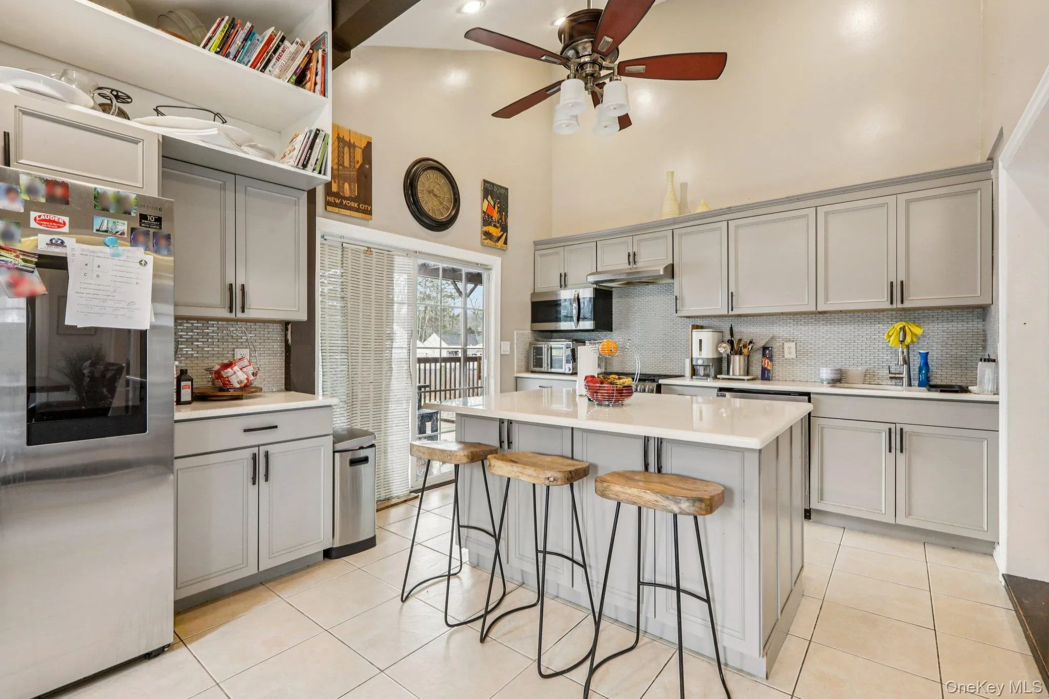 Kitchen with gray cabinets, stainless steel appliances, light tile patterned floors, ceiling fan, and a breakfast bar Kitchen with gray cabinets, stainless steel appliances, light tile patterned floors, ceiling fan, and a breakfast bar