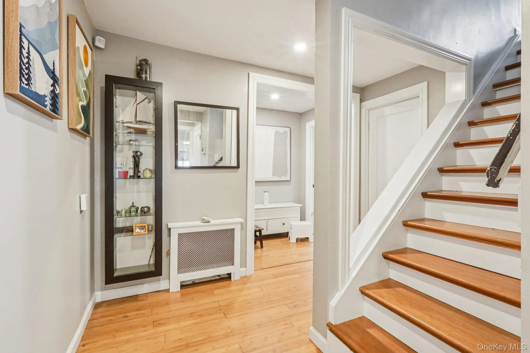 Stairway featuring radiator heating unit, wood finished floors, and recessed lighting Stairway featuring radiator heating unit, wood finished floors, and recessed lighting