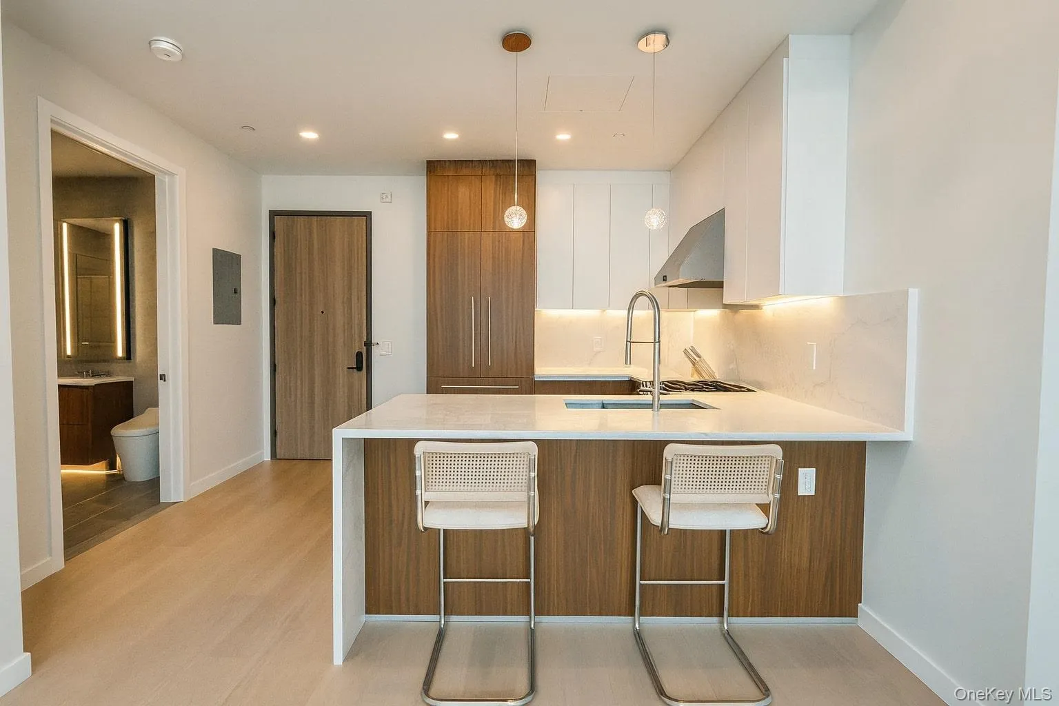 Kitchen featuring brown cabinetry, a kitchen breakfast bar, modern cabinets, light stone counters, and a peninsula Kitchen featuring brown cabinetry, a kitchen breakfast bar, modern cabinets, light stone counters, and a peninsula