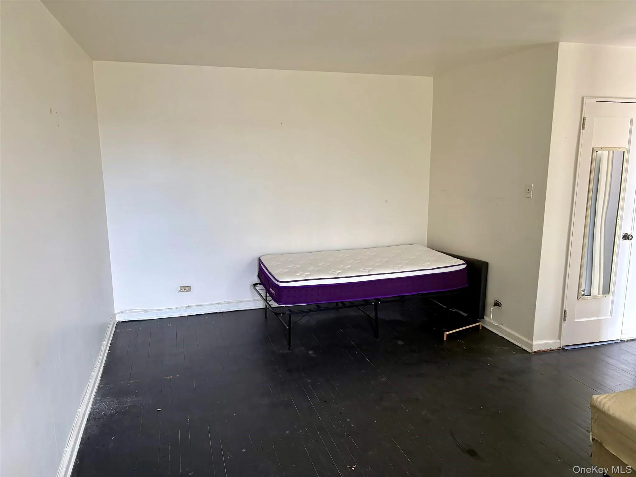 Room with bed featuring dark wood-style flooring and baseboards Room with bed featuring dark wood-style flooring and baseboards