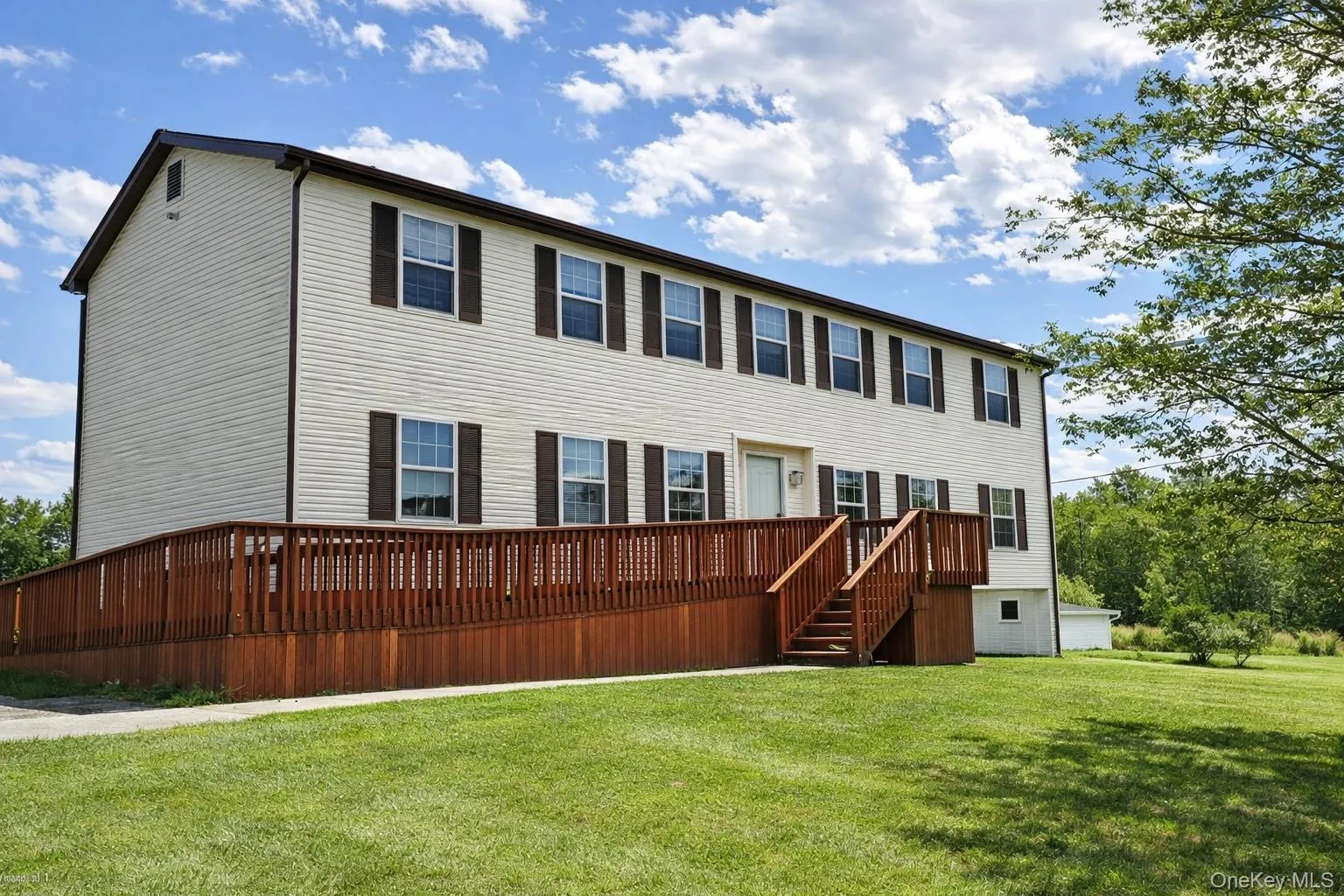 view of house with a wooden deck and a yard view of house with a wooden deck and a yard