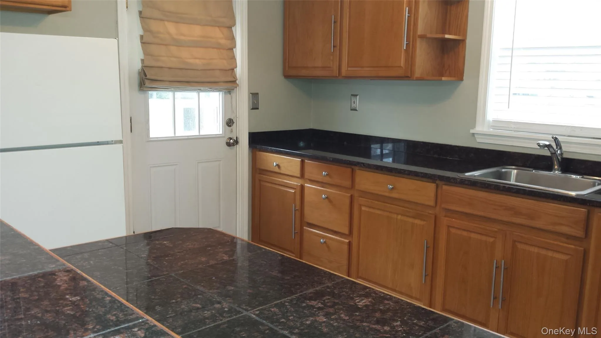 Kitchen featuring white refrigerator, a wealth of natural light, and sink Kitchen featuring white refrigerator, a wealth of natural light, and sink